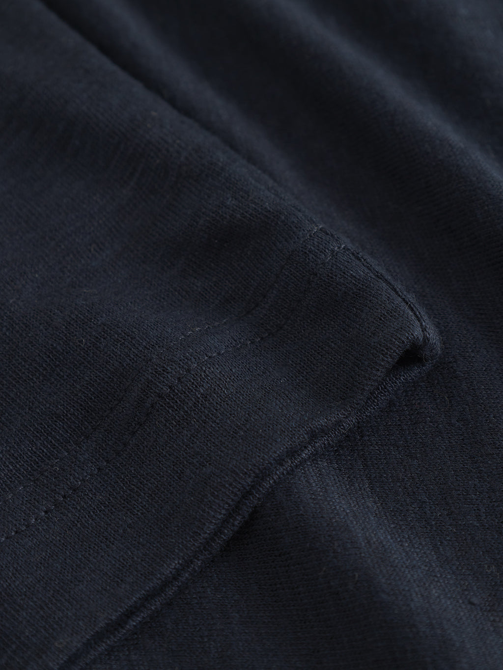Close-up of Trevor - Navy by Gabba, showcasing dark fabric with visible stitching and texture like a premium t-shirt. The material is smooth and slightly glossy under light, promising comfort. A diagonal seam in the image highlights the craftsmanship.