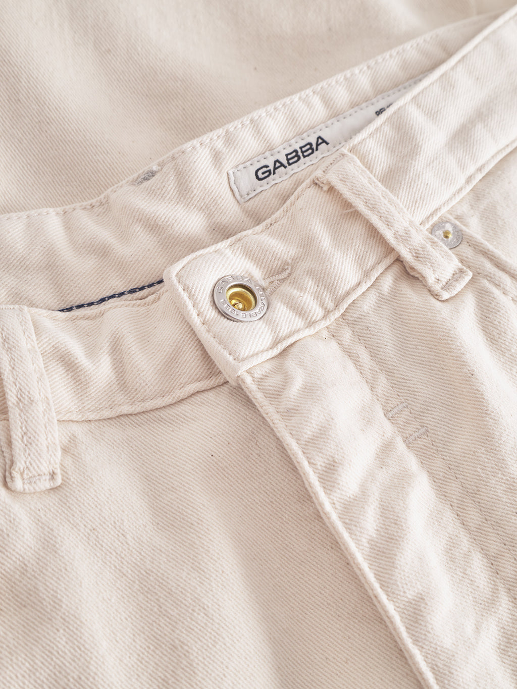 Close-up of Gabbas Maxwell Luis Cargo Shorts in ecru, crafted from non-stretch fabric. The visible button and waistband highlight workwear quality, with clear texture and stitching details reflecting durability.