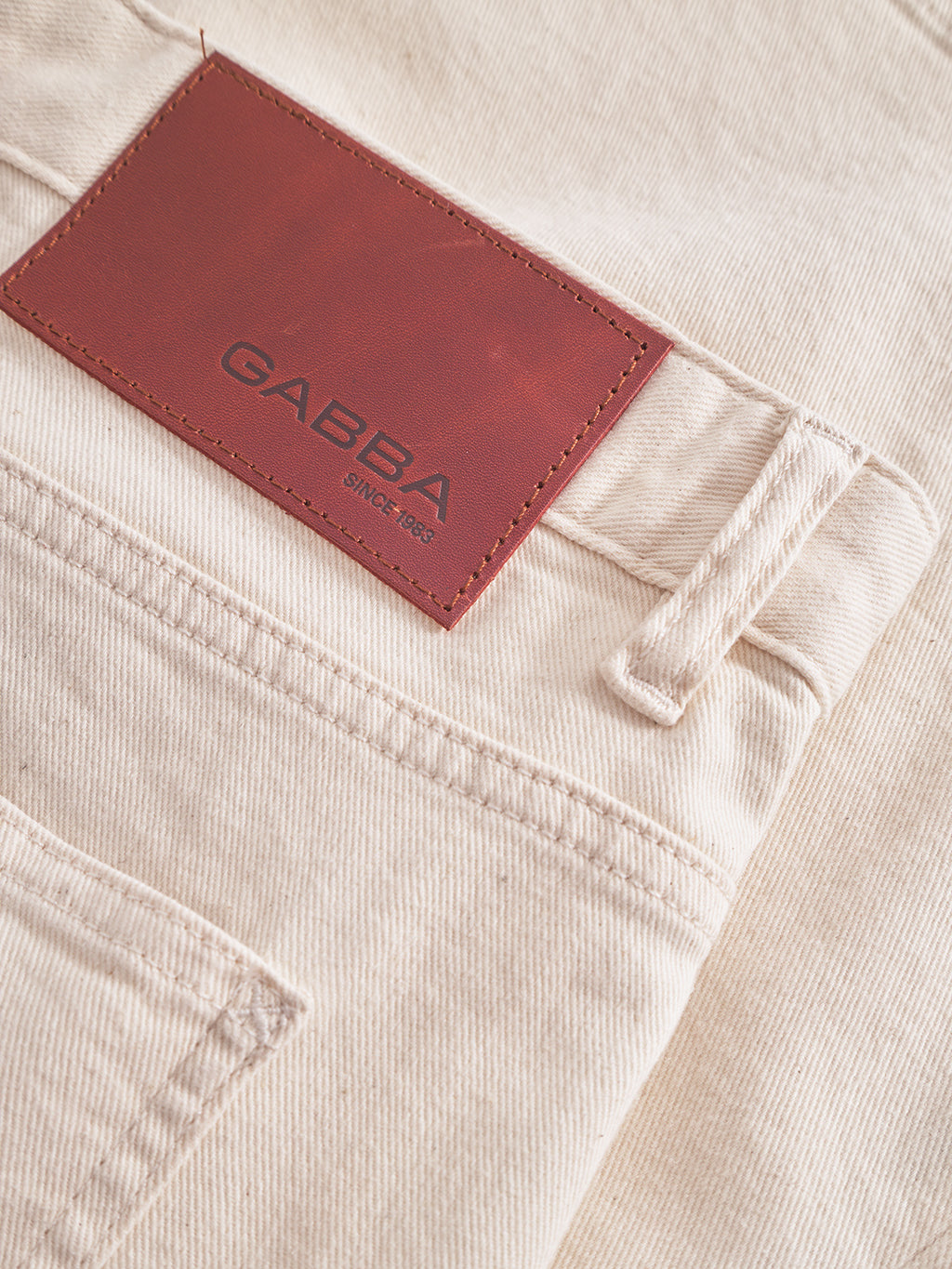 Close-up of beige Maxwell Luis Cargo Shorts in non-stretch fabric, featuring a brown leather patch on the waistband embossed with Gabba Since 1983, showcasing a back pocket, belt loop, and workwear-inspired fine stitch details.
