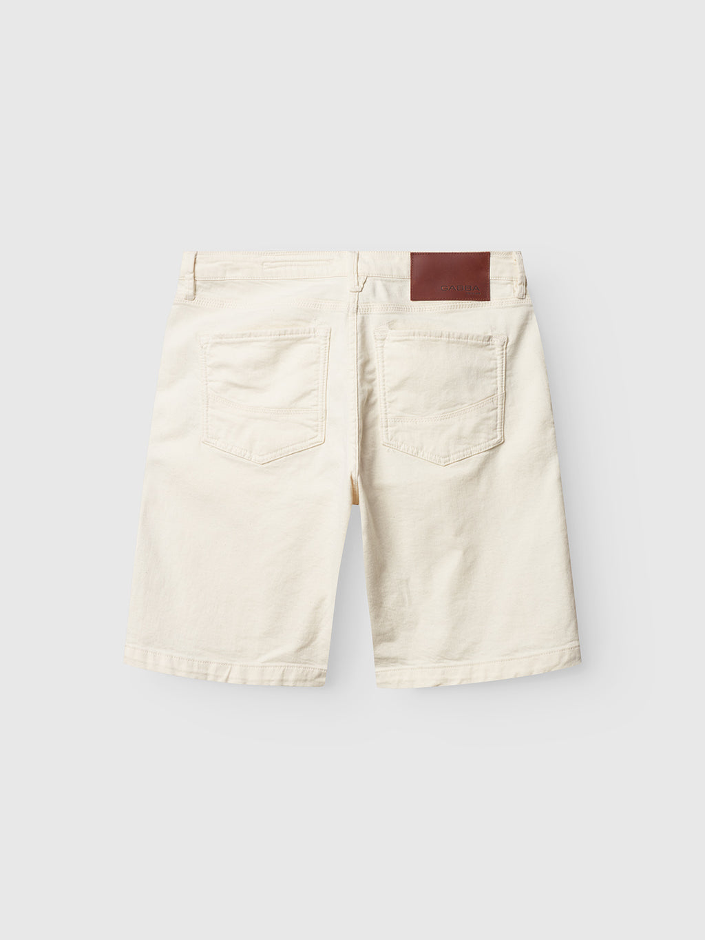 The Maxor Luis Shorts - Ecru by Gabba are classic beige denim shorts with two rear pockets, a brown leather patch on the waistband, and comfort stretch for ease of movement.