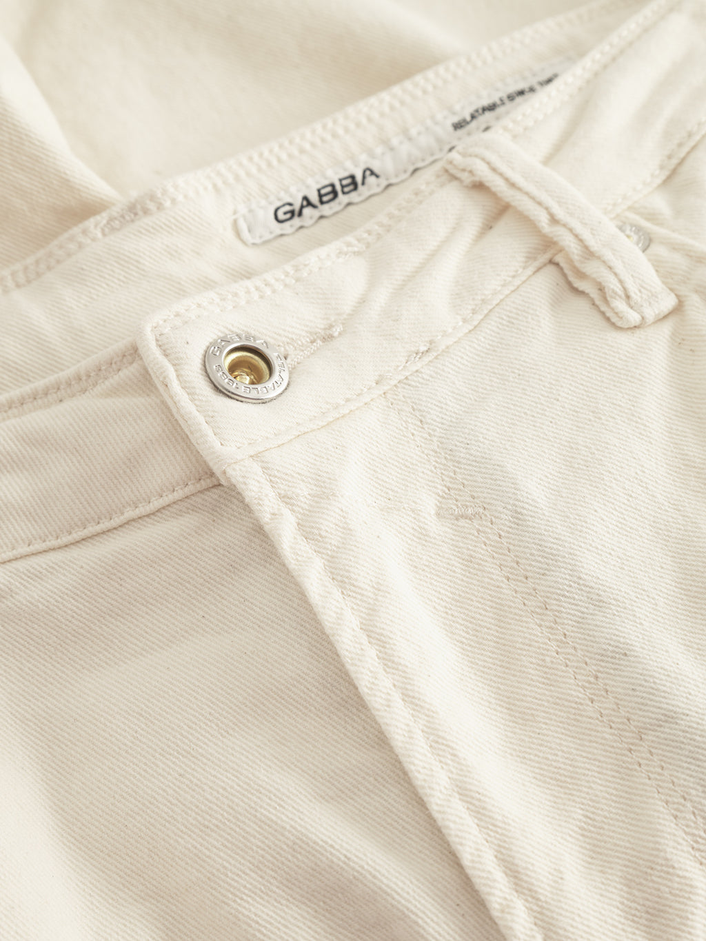 Close-up of Maxor Luis Shorts in ecru highlighting the waistband and button. The slightly textured fabric offers a comfortable stretch feel. A visible Gabba label inside ensures style meets comfort effortlessly.