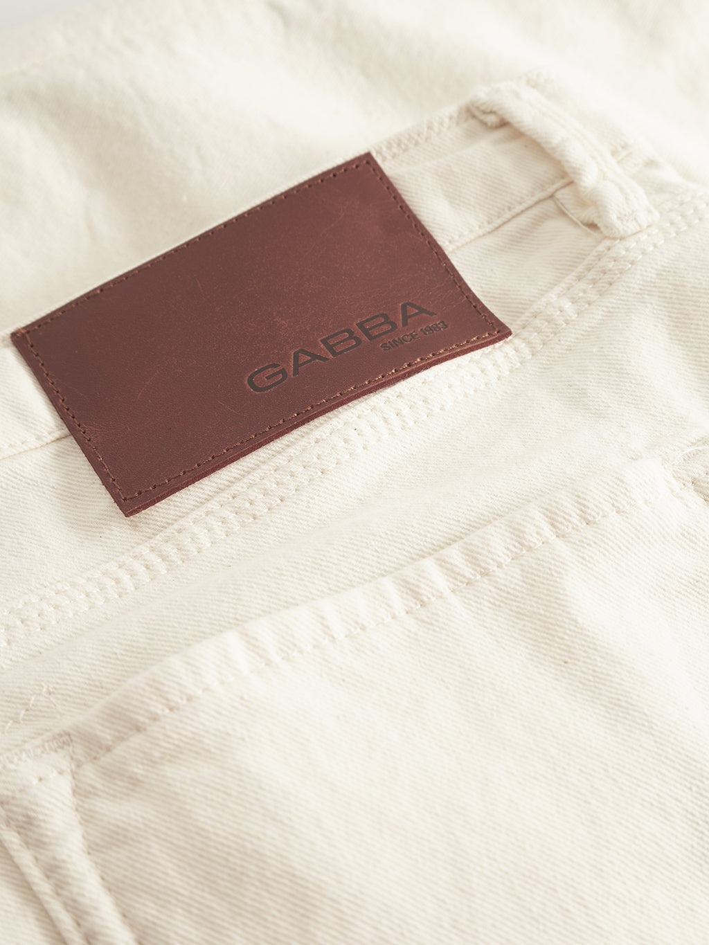 Close-up of Maxor Luis Shorts - Ecru by Gabba, showing the back pocket with a brown leather patch and GABBA embossed. The fabric texture and stitching emphasize the comfort stretch design, ensuring style and ease for any outfit.