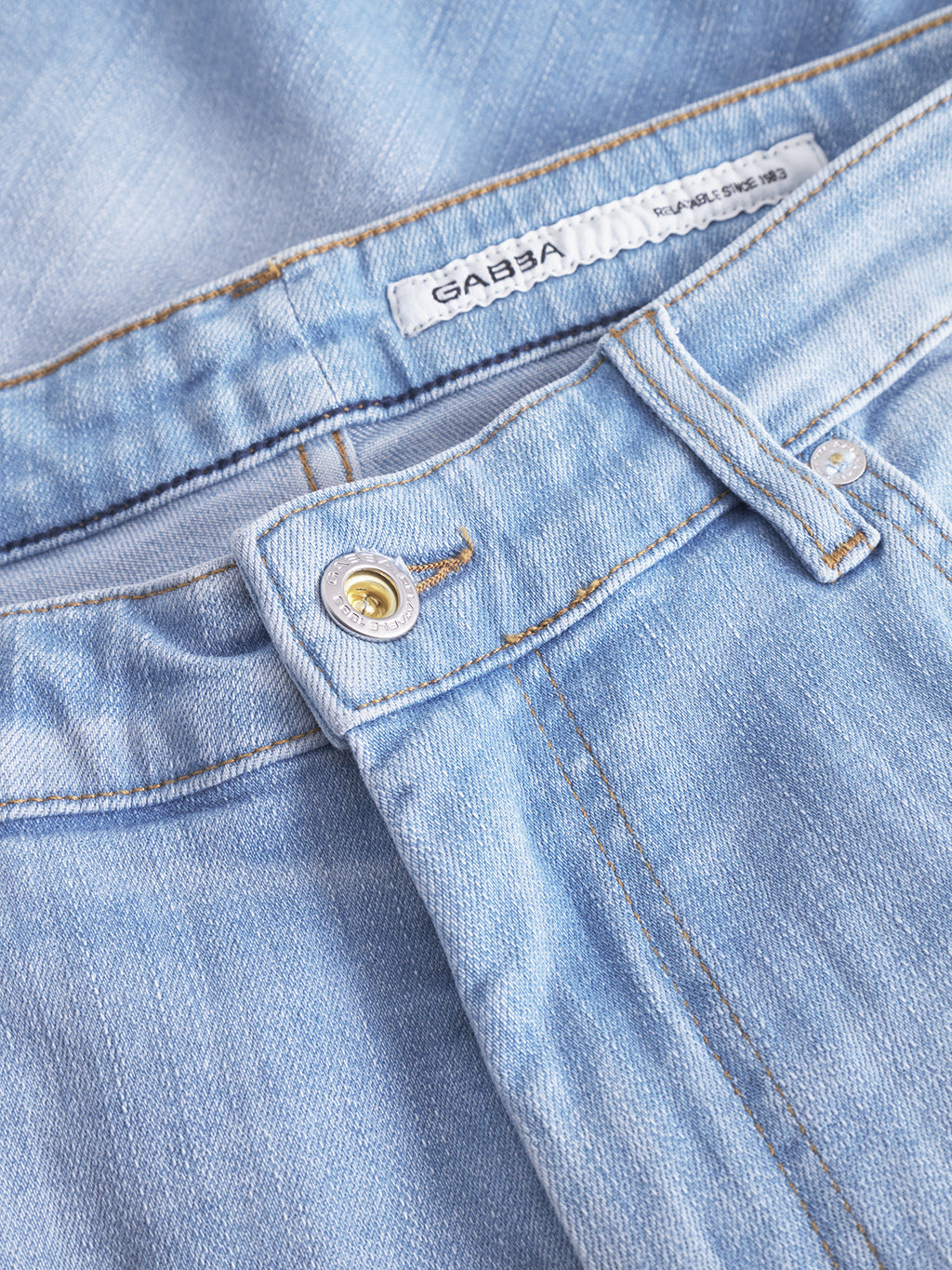 Close-up of Gabbas Markus Selvedge Shorts Limited in light blue denim, highlighting a metal button, zipper, folding at the waistband, and intricate stitching details.