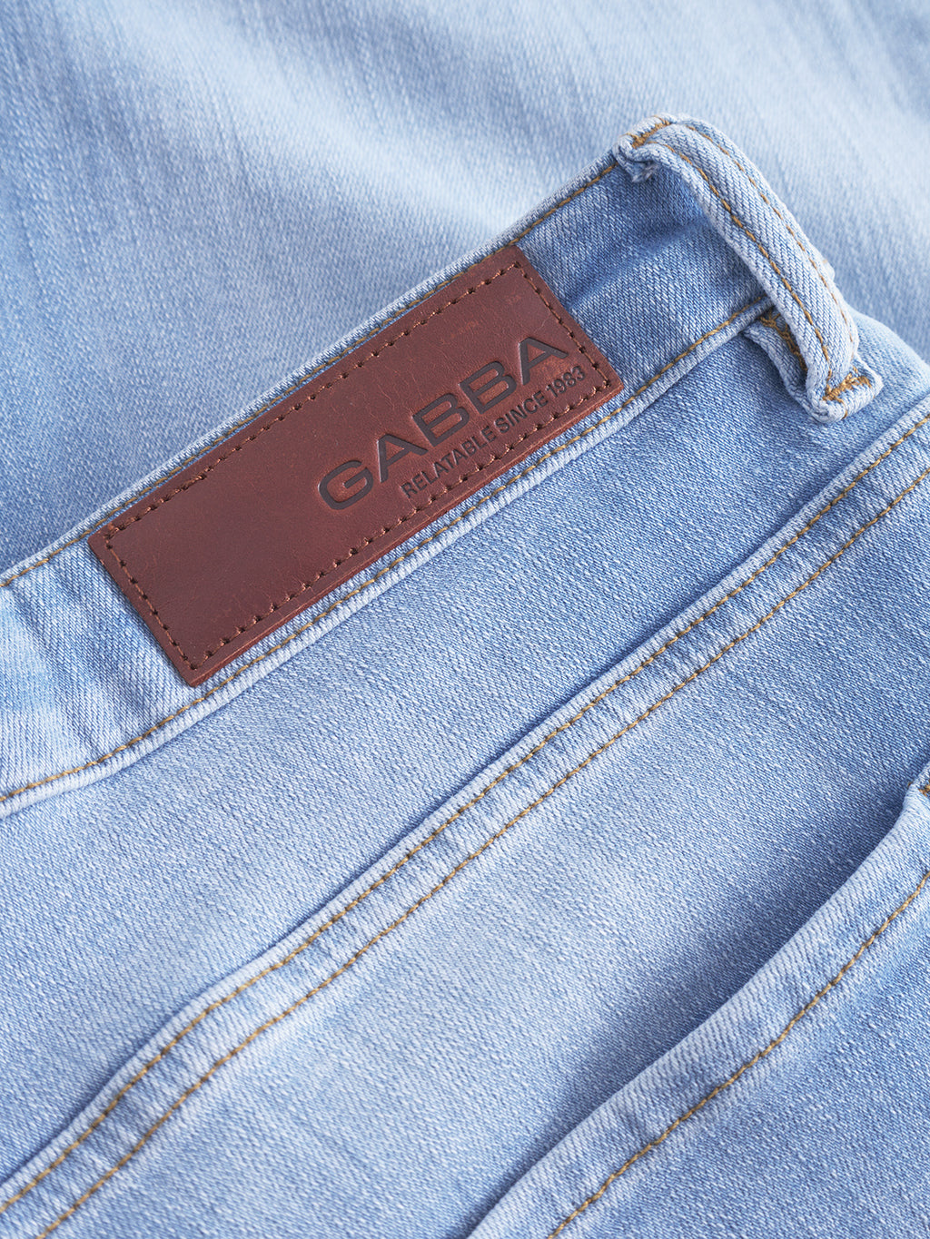 Close-up of Markus Selvedge Shorts Limited in light blue denim, featuring a brown leather patch embossed with Gabba, Reliable Since 1983. Emphasis on comfortable fit and stitching details highlights the fabric texture, waistband, and pockets.