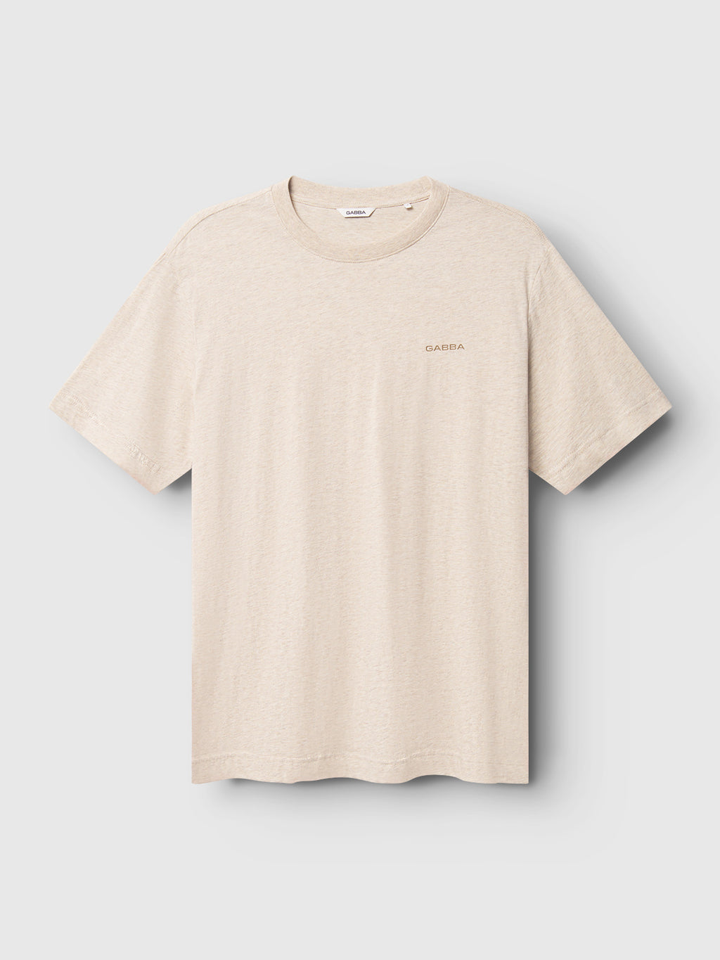 The Dune Melange SS - Lt. Sand by Gabba is an ultra-soft melange jersey T-shirt in plain beige, adorned with a small, discreet Gabba logo on the left chest, set against a light gray background.