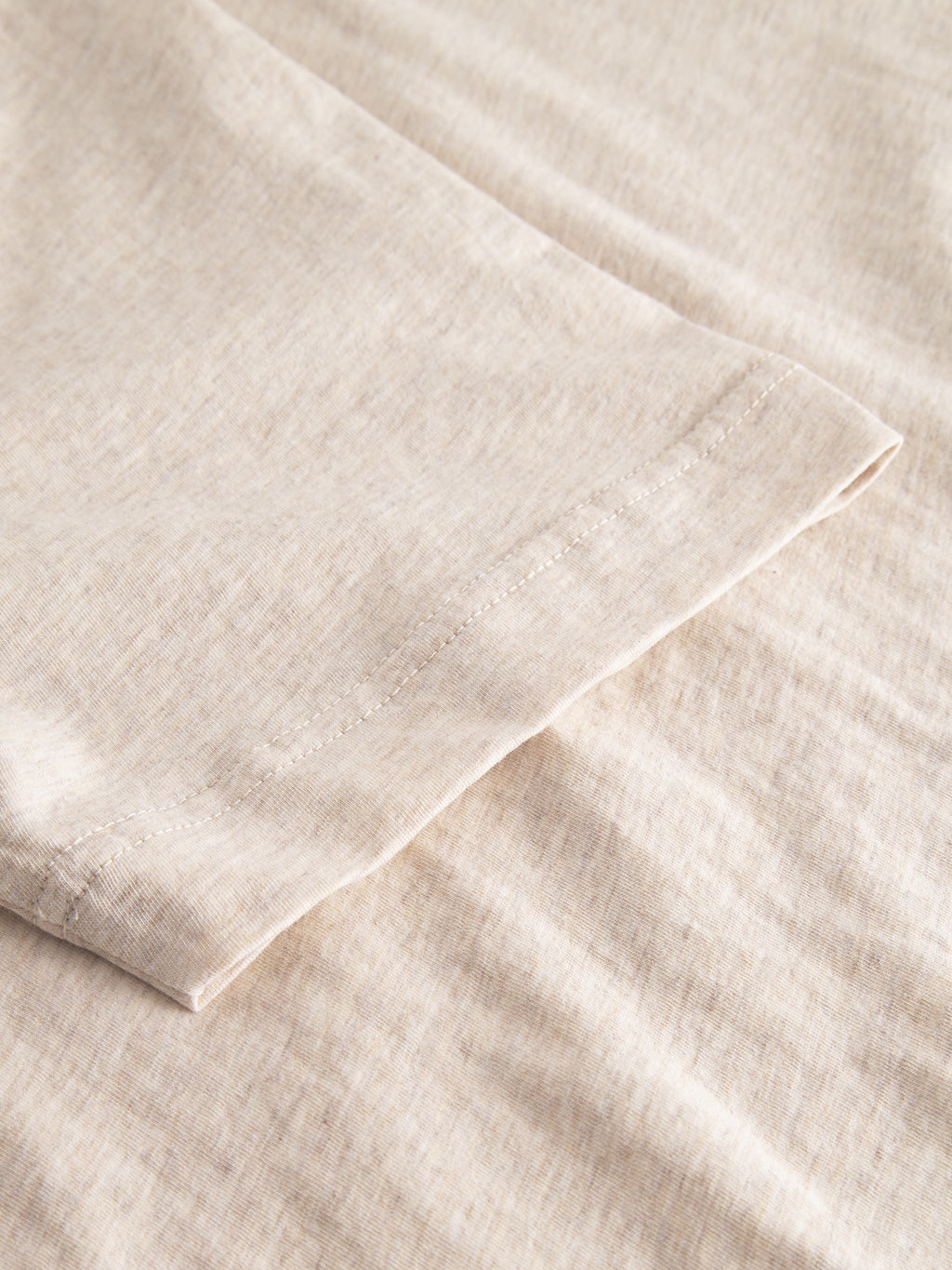 Close-up of the ultra-soft Dune Melange SS - Lt. Sand by Gabba, highlighting the stitching detail and texture of the beige fabric.