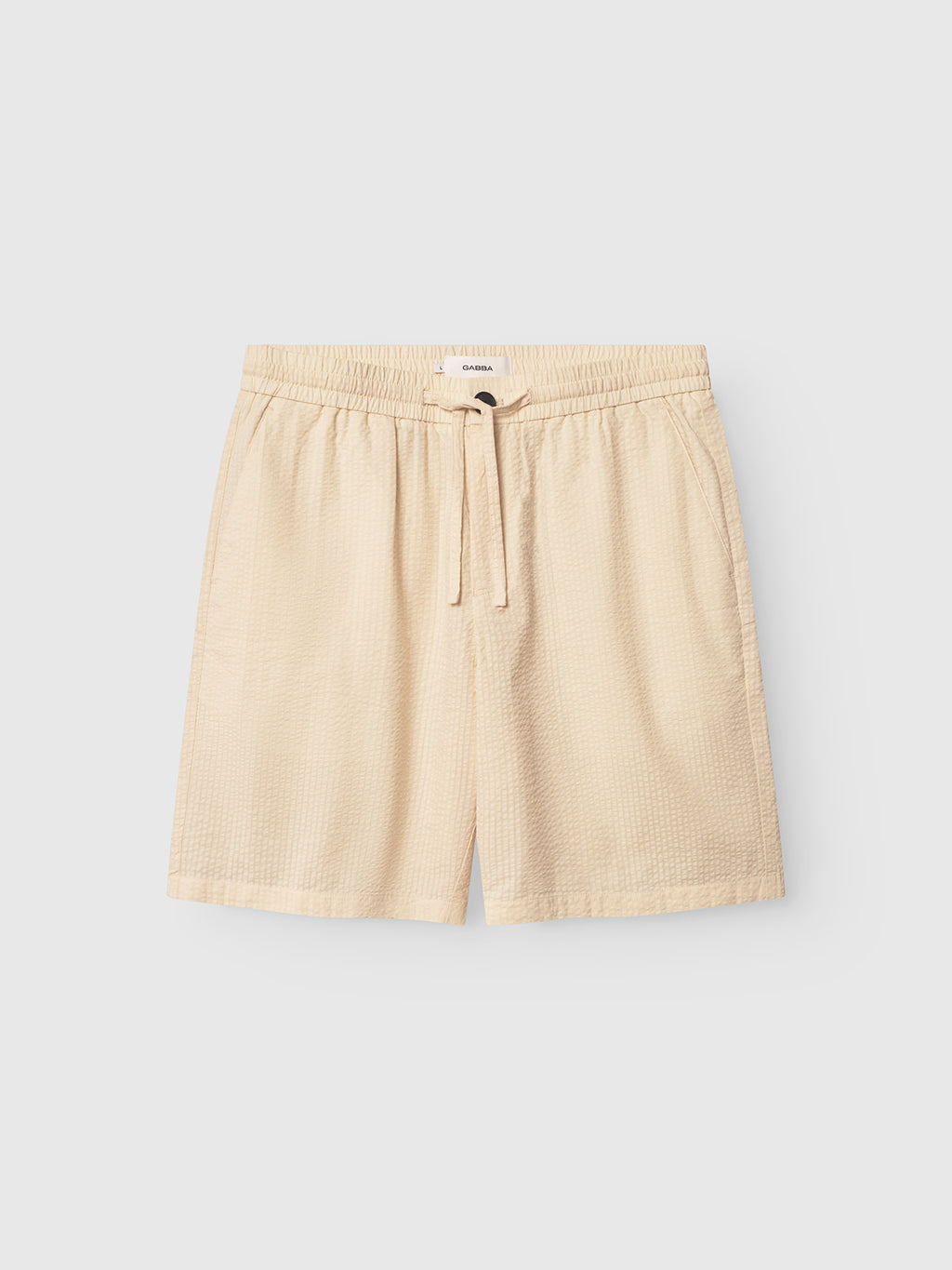 The Tommi Seer - Ecru Light by Gabba are beige drawstring shorts made from premium seersucker fabric, featuring an elastic waistband and a subtle texture, showcased on a plain white background.