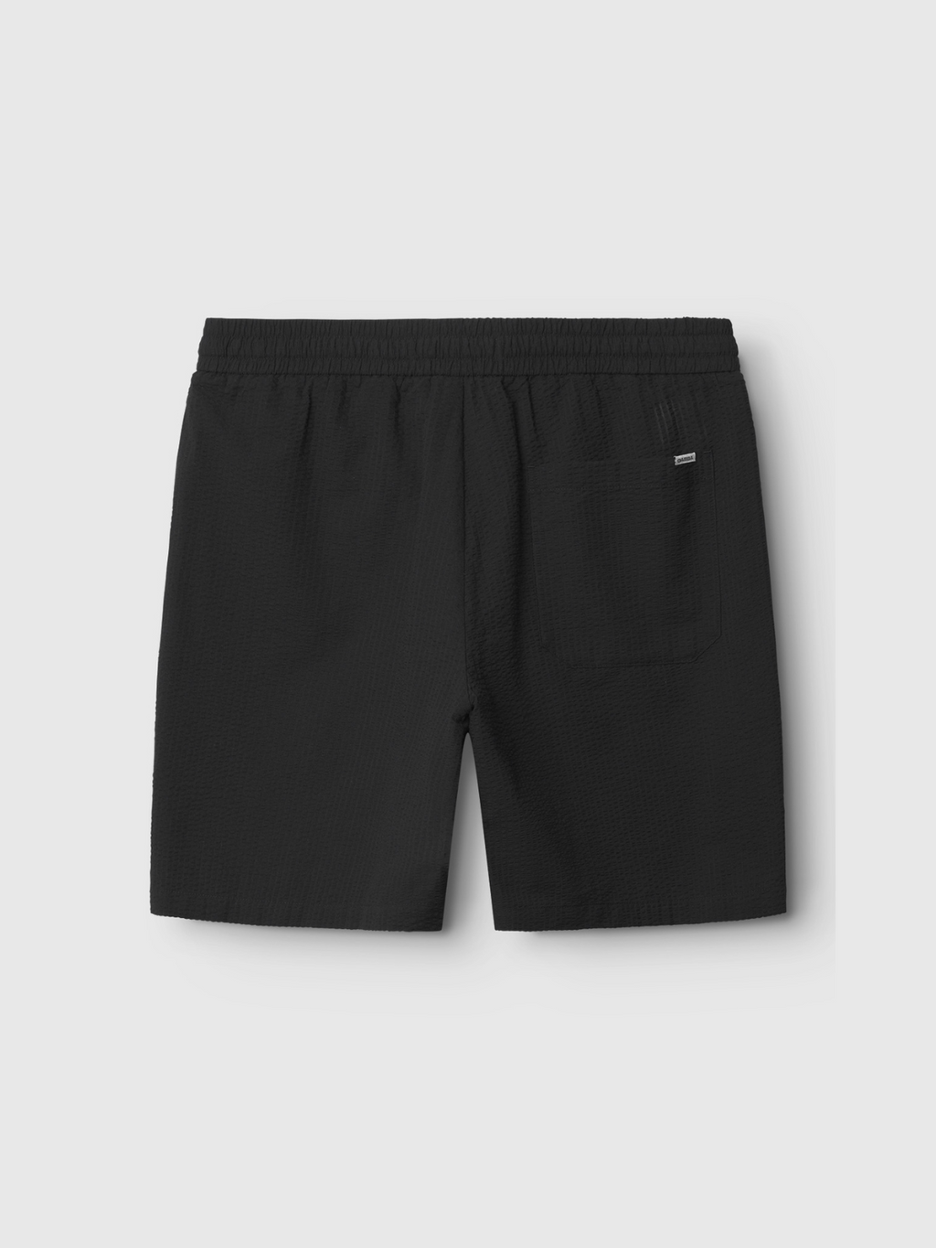 The Gabba Tommi Seer - Black shorts are shown from the back, featuring an elastic waistband and a single right-side patch pocket. Made from lightweight seersucker fabric, theyre displayed against a plain light background.