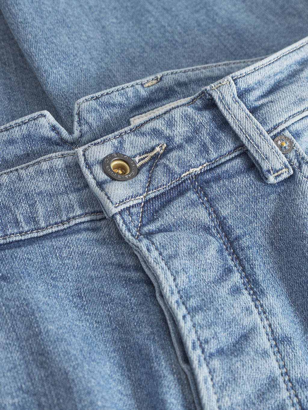A close-up of the Alex Foursix Limited - Lt. Blue Denim jeans by Gabba, highlighting the button and zipper area. The fashion-forward design includes visible stitching, belt loops, and a classic denim texture in a light blue shade.