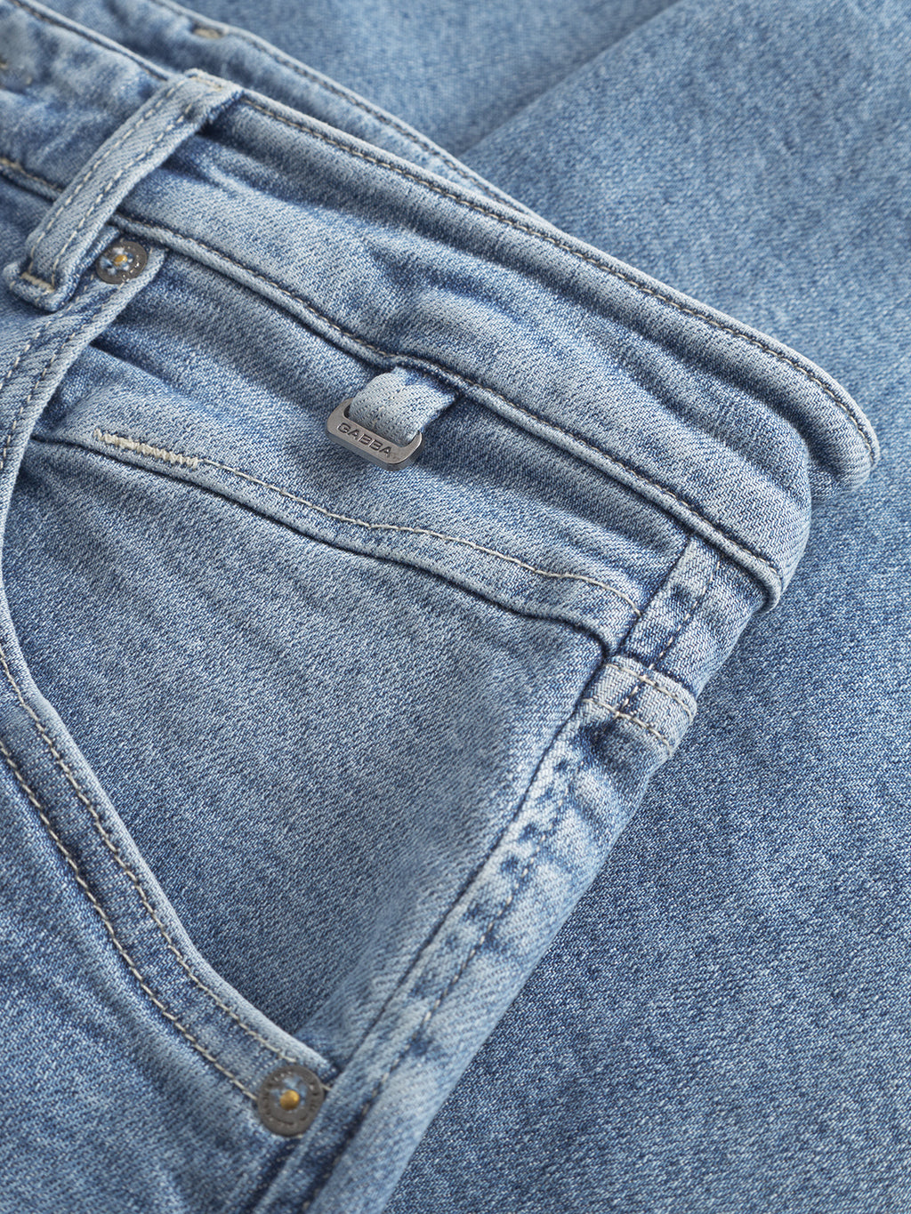 Close-up of Gabbas Alex Foursix Limited - Lt. Blue Denim jeans, showcasing a front pocket, large back pockets, belt loops, and a metallic button. The fashion-forward design emphasizes the textured fabric and classic denim weave. The jeans are laid flat and partially folded.