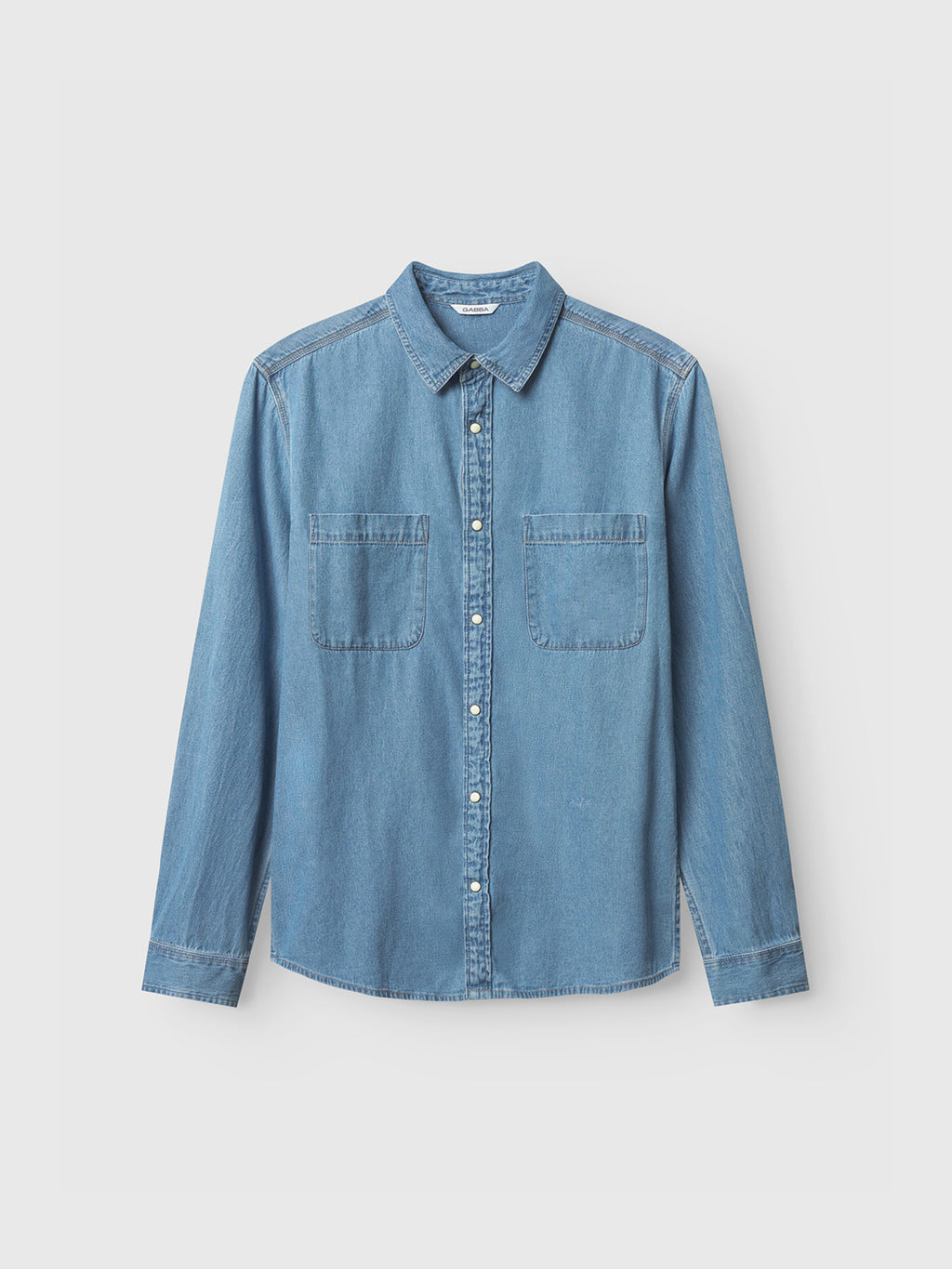 The Sven Reg Denim LS by Gabba is a light blue denim button-up shirt with long sleeves and two chest pockets, set against a plain white background for a timeless appeal.