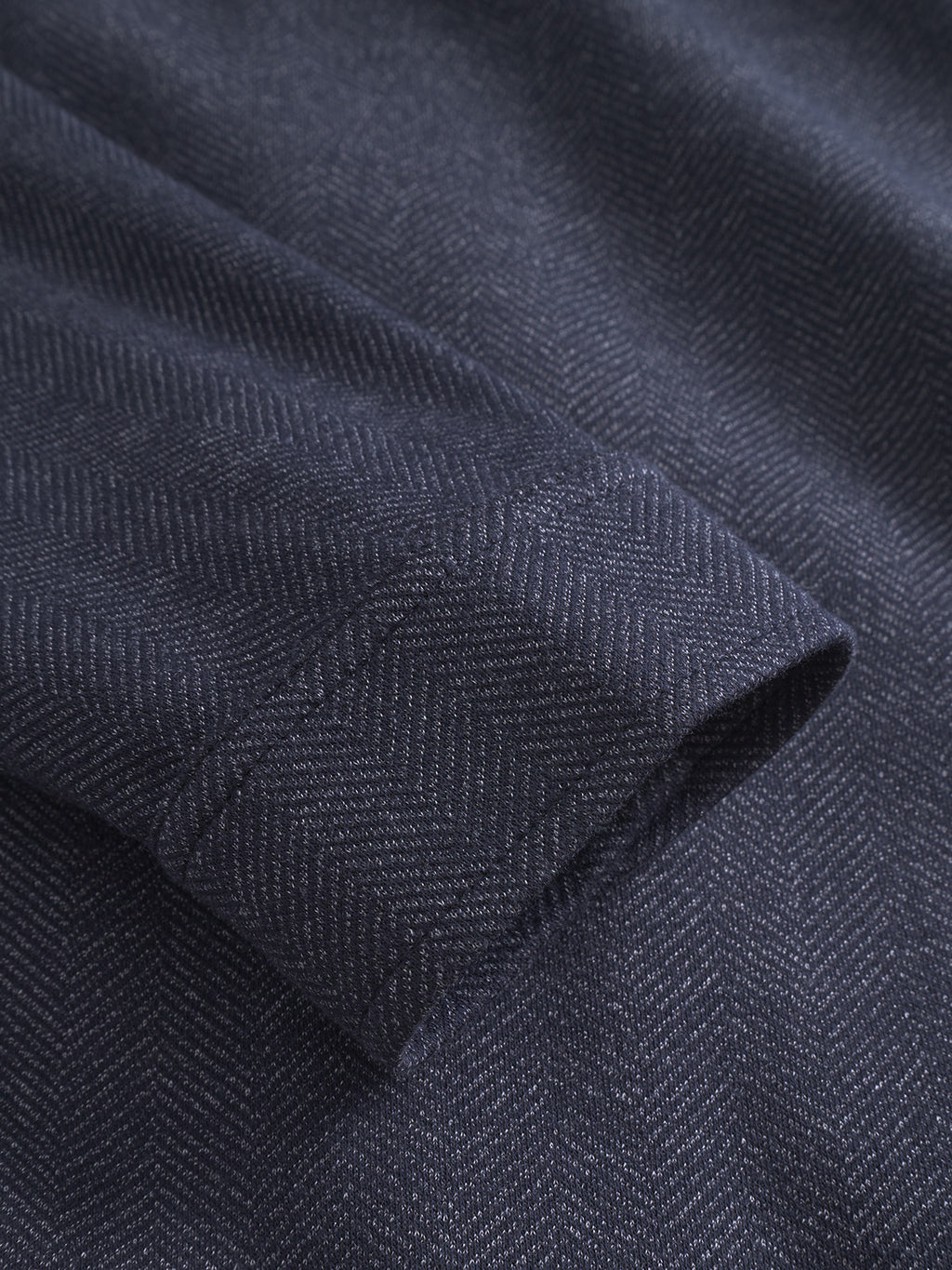 Close-up of the dark navy blue sleeve from Gabbas Peter Tweed jacket, featuring a subtle herringbone pattern. Its soft texture with gray zigzag lines, tailored fit, and neatly stitched hem create a sophisticated look.