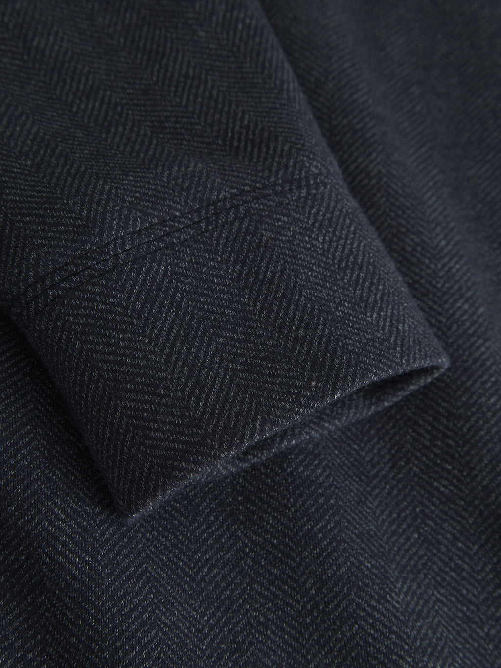 Close-up of Gabbas Nik Tweed - Navy, showcasing rich tweed fabric with a subtle herringbone pattern. Neatly folded edge highlights the fine detail and craftsmanship, ideal for an everyday jacket with elegant hidden side pockets.