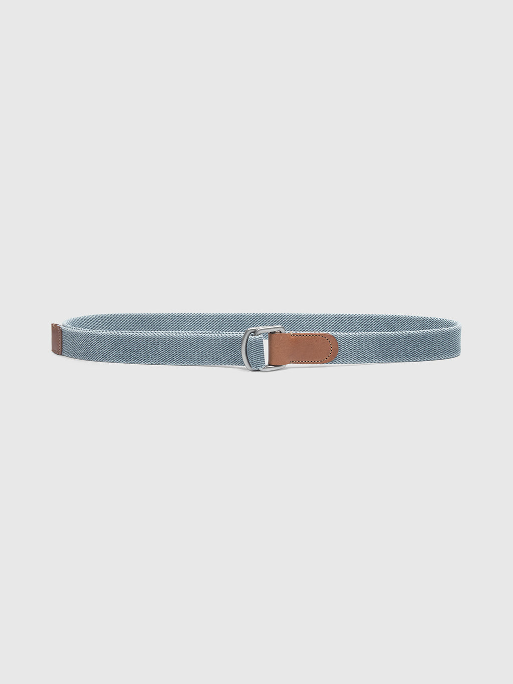 The Manica Denim Belt by Gabba is a high-quality light blue woven cotton accessory featuring a sleek silver metal D-ring buckle and brown leather accents on the ends, presented on a plain white background.