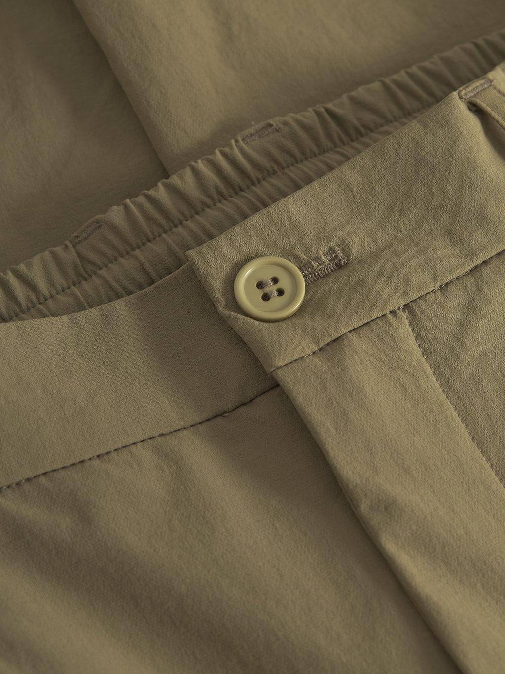 Close-up of Gabbas olive green Napoli 19 Tech - Army pants showcasing a four-hole button closure and elastic waistband. The versatile design combines comfort and style with visible stitching and fabric texture highlighting the garments detail and quality.