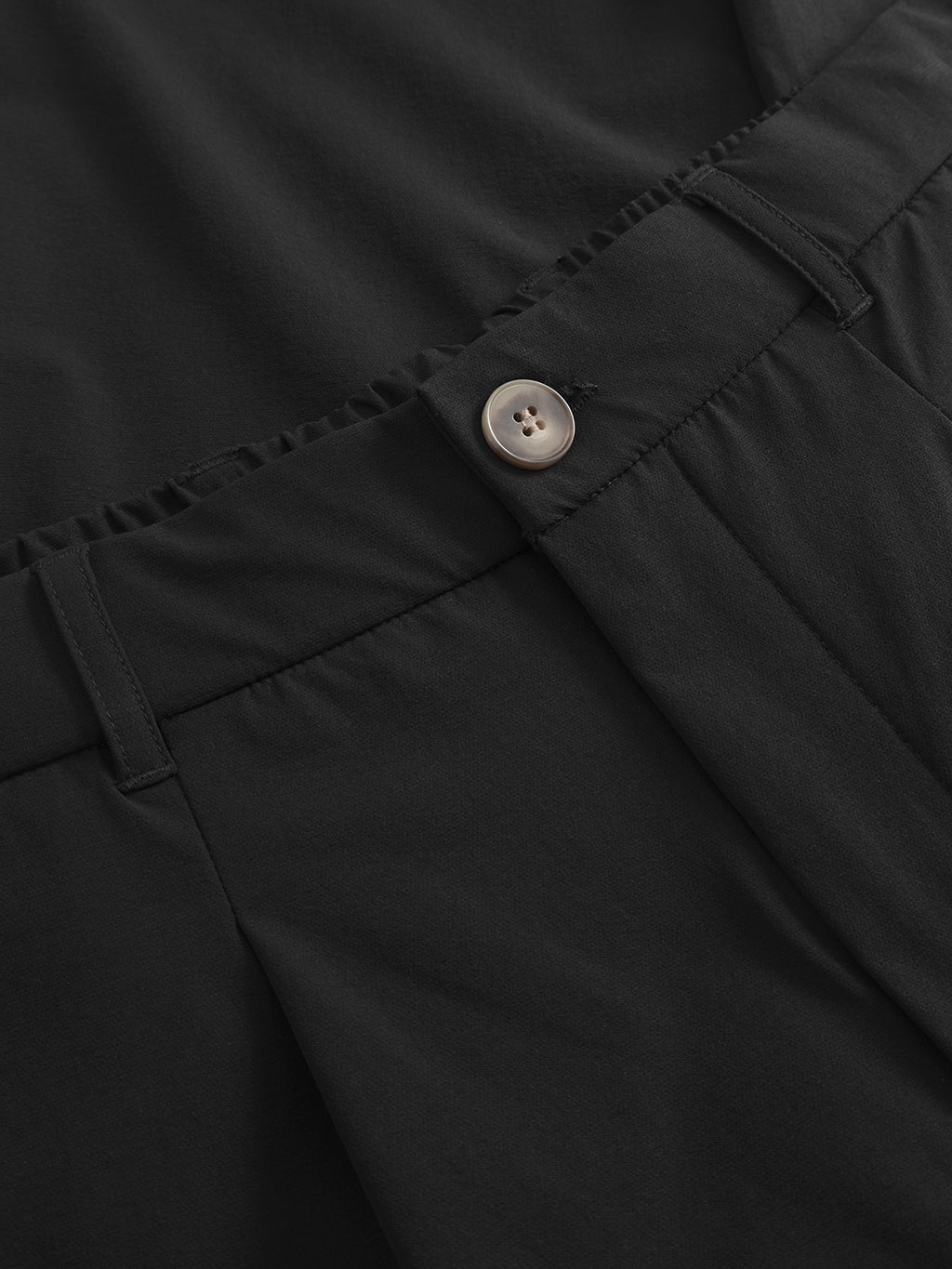 Close-up of Gabbas Napoli 19 Tech - Black pants shows a button and zipper closure, smooth fabric with slight gathers at the waist for comfort, plus belt loops for versatility.