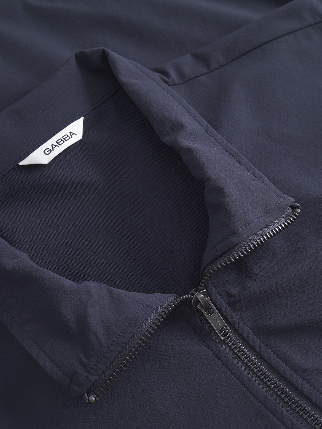 Close-up of the Gabba Nik Tech - Navy zip-front garment with a folded collar and a white Gabba label inside the neckline—ideal for an on-the-go lifestyle.