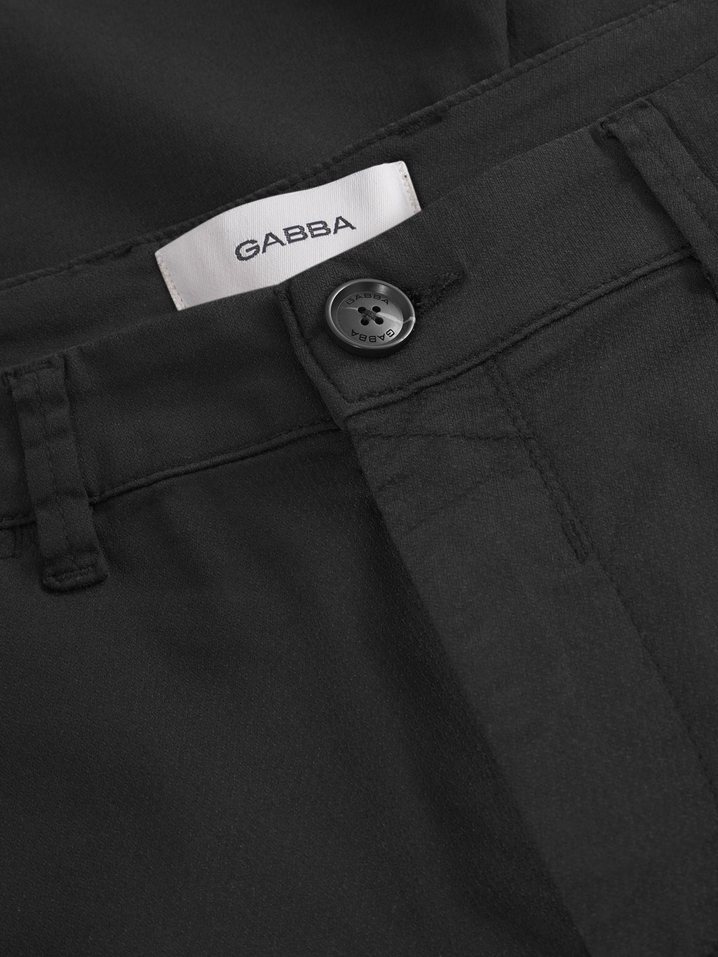 Close-up of the waistband and button of the Gabba Paul K3280 Cargo Dale pants in black. A visible white Gabba label, detailed stitching, and textured fabric showcase their stylish and practical design.