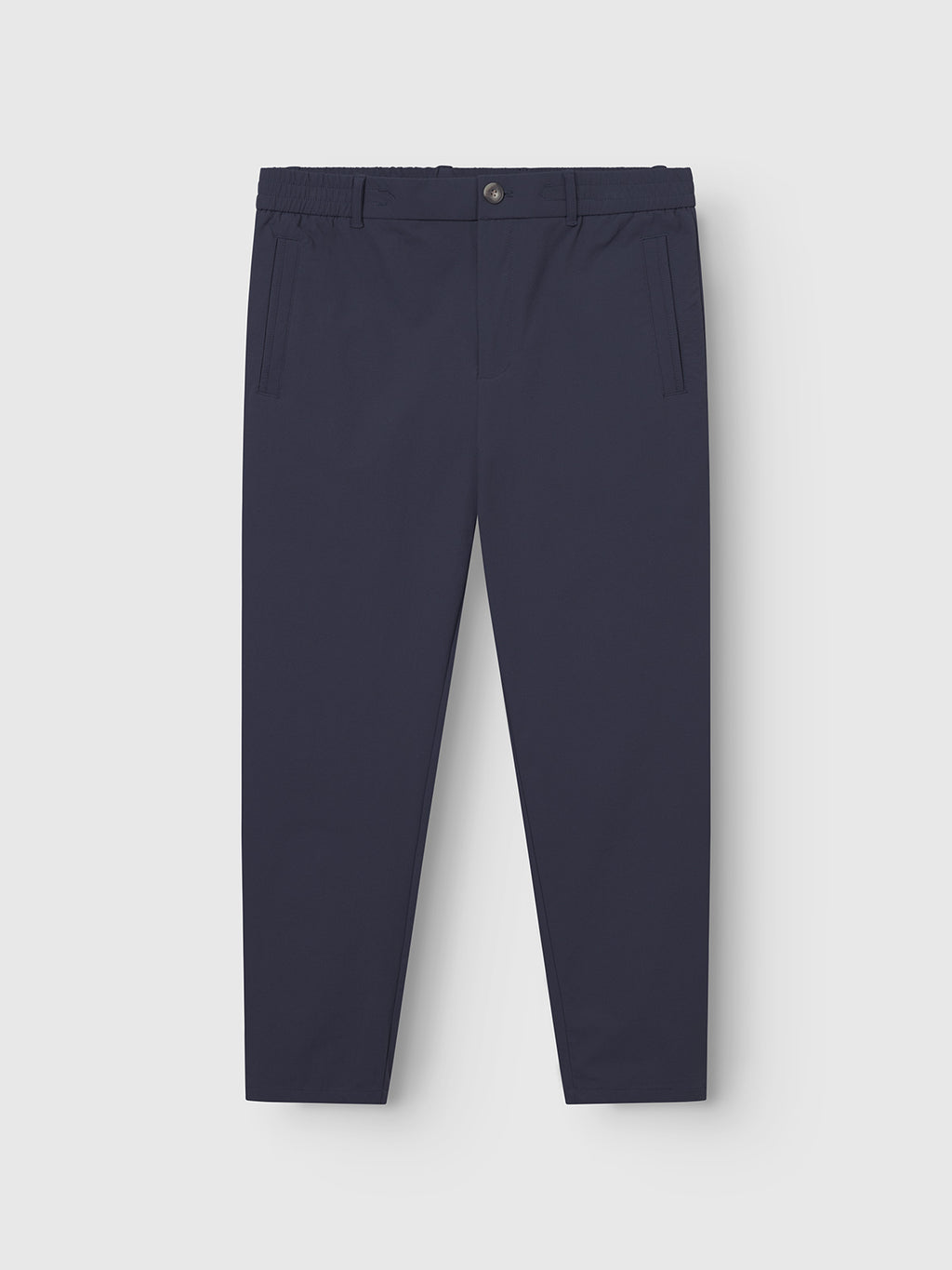 The Monza Tech - Navy trousers by Gabba feature a relaxed straight fit with an elastic waistband and a single button closure. Made from tech fabric, they are displayed flat on a light gray background, showcasing side pockets and a tapered leg design.