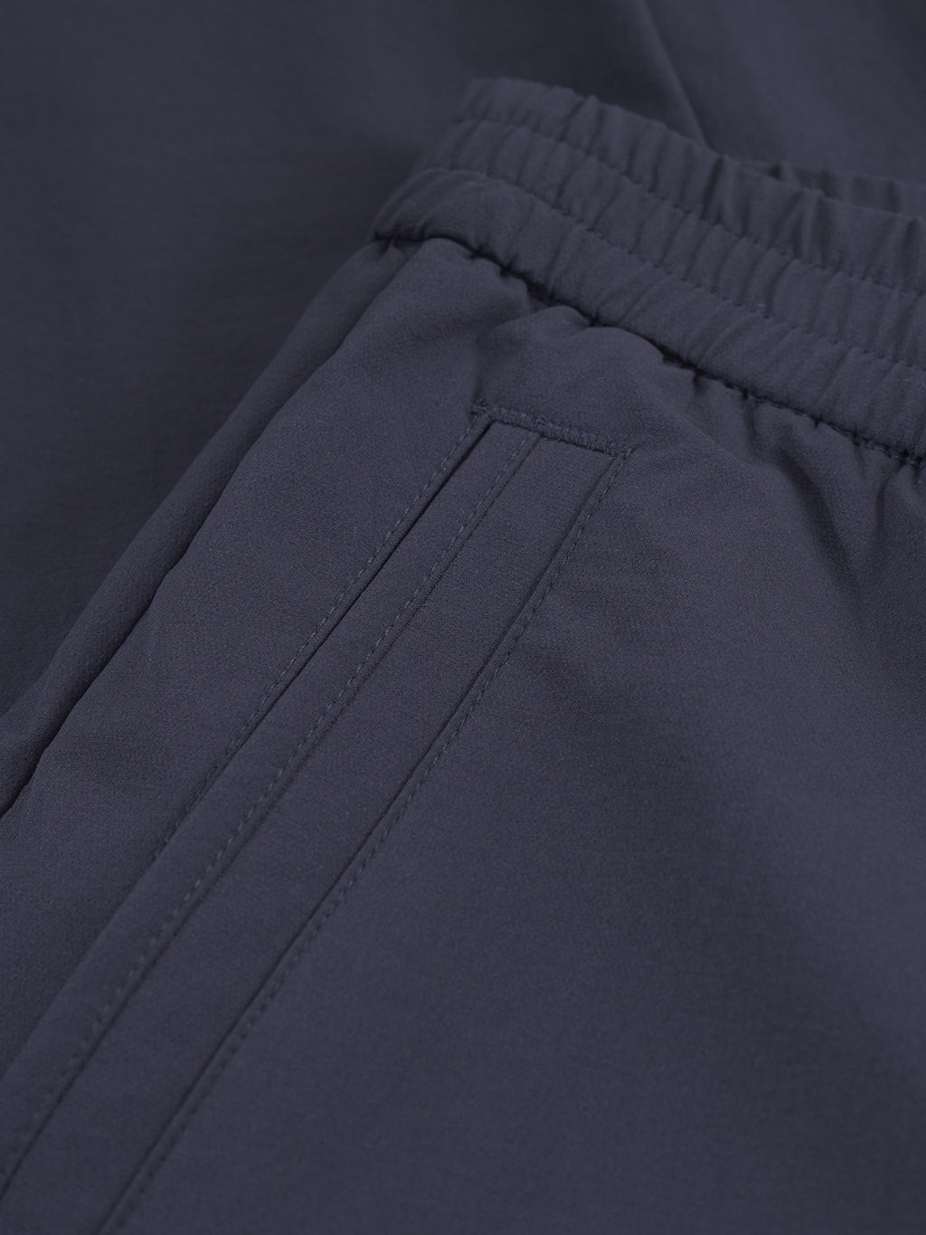 Close-up of Monza Tech - Navy track pants by Gabba, featuring a side pocket and elastic waistband. Made from smooth, lightweight tech fabric, theyre ideal for casual or athletic wear.
