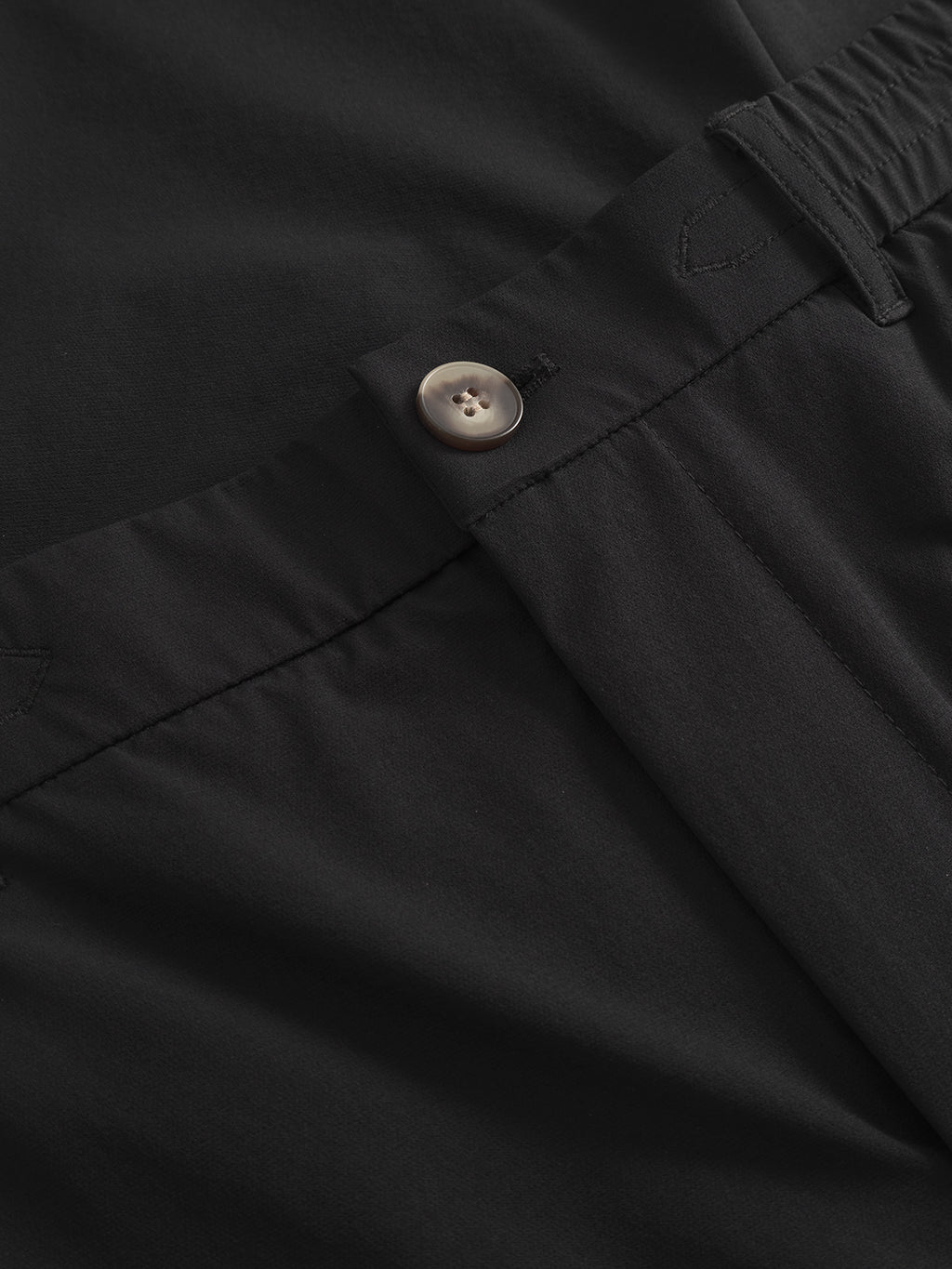 Close-up of Gabbas Monza Tech - Black pants showcasing a button and elastic waistband, with smooth tech fabric and neat stitching in a relaxed straight fit.