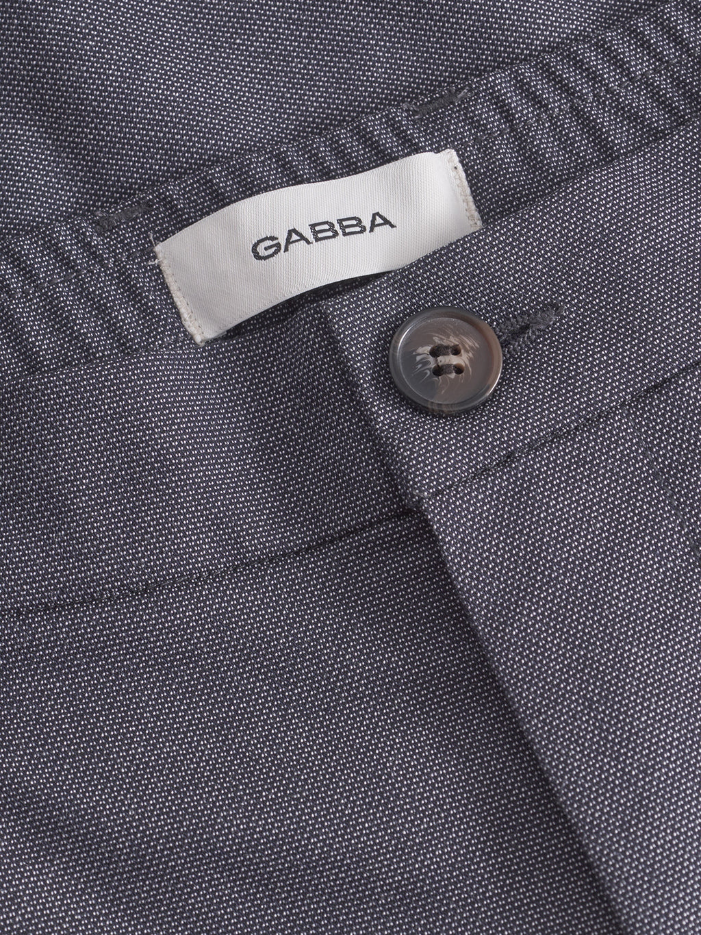 A close-up of navy Napoli 19 Carre pants featuring a subtle texture shows the Gabba tag above the waistband. Known for comfort, these pants include a button with a neatly stitched buttonhole.