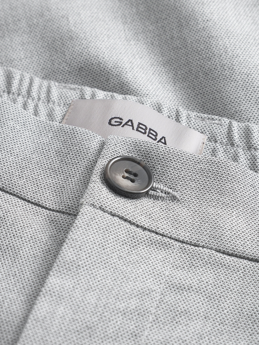Close-up of Gabba Napoli 19 Carre - Lt. Grey pants featuring textured fabric, a black button, and a partially visible white Gabba label above the waistband for classic style and comfort.