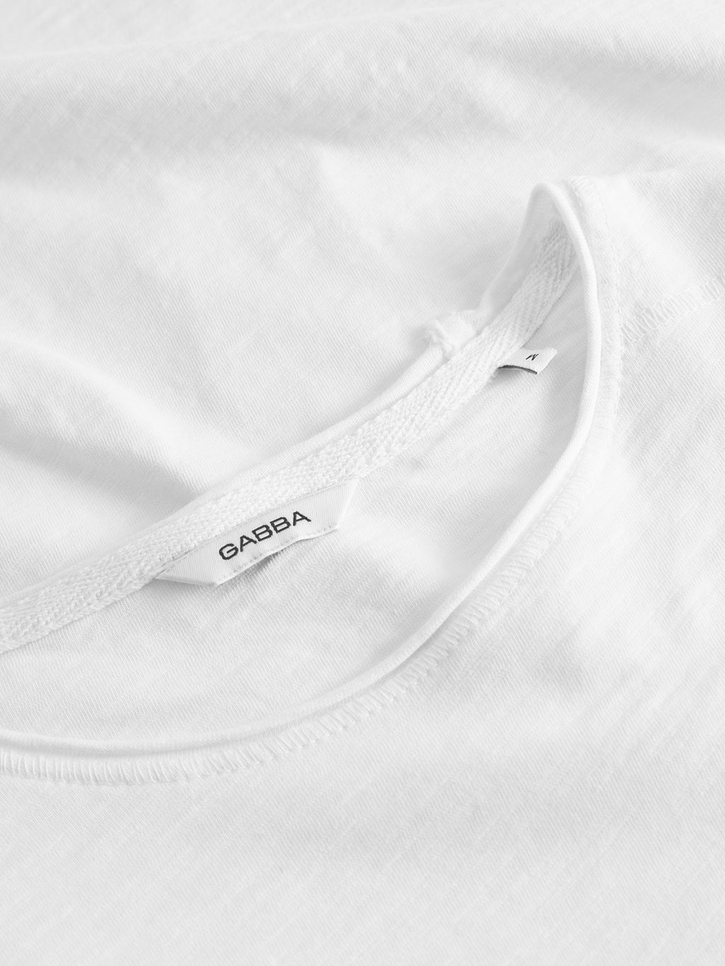 Close-up of the Gabba Kostant New SS - White T-shirt, showcasing the neckline, branded fabric tag, and detailed stitching on the slub cotton fabric for a casual look.