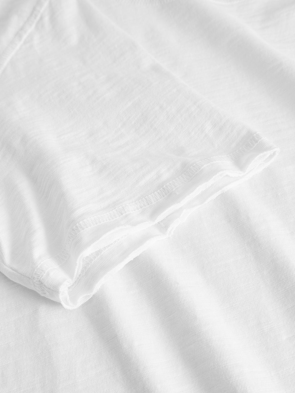 Close-up of the short sleeve and shoulder of the Gabba Kostant New SS - White, showcasing the lightweight slub fabric’s textured stitching detail for a casual look.