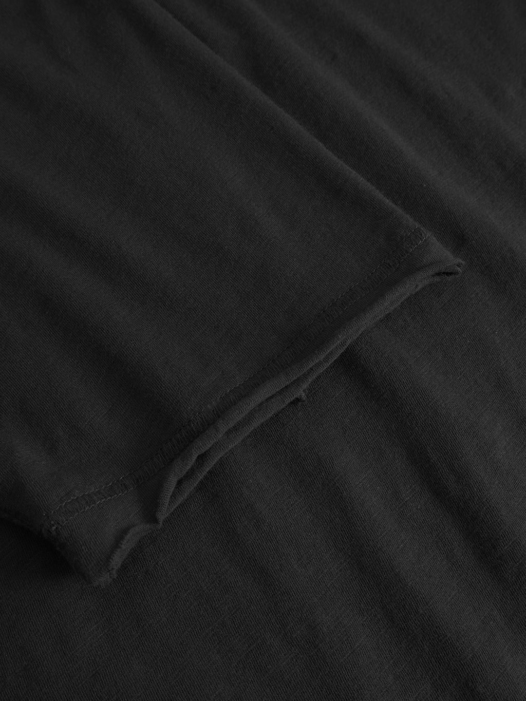 Close-up of the Kostant New SS - Meteorite by Gabba, featuring black slub fabric with visible stitching and a rolled hem on the sleeve, emphasizing its modern casual style and relaxed fit texture.
