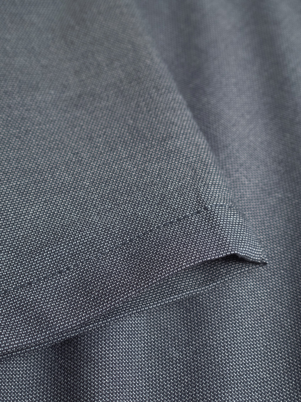 Close-up of Gabba’s Monza Button Carre in Navy, featuring a fine textured weave ideal for crafting relaxed straight pants. Its neatly hemmed edges create gentle folds and shadows, while the elastic waist enhances comfort and style.