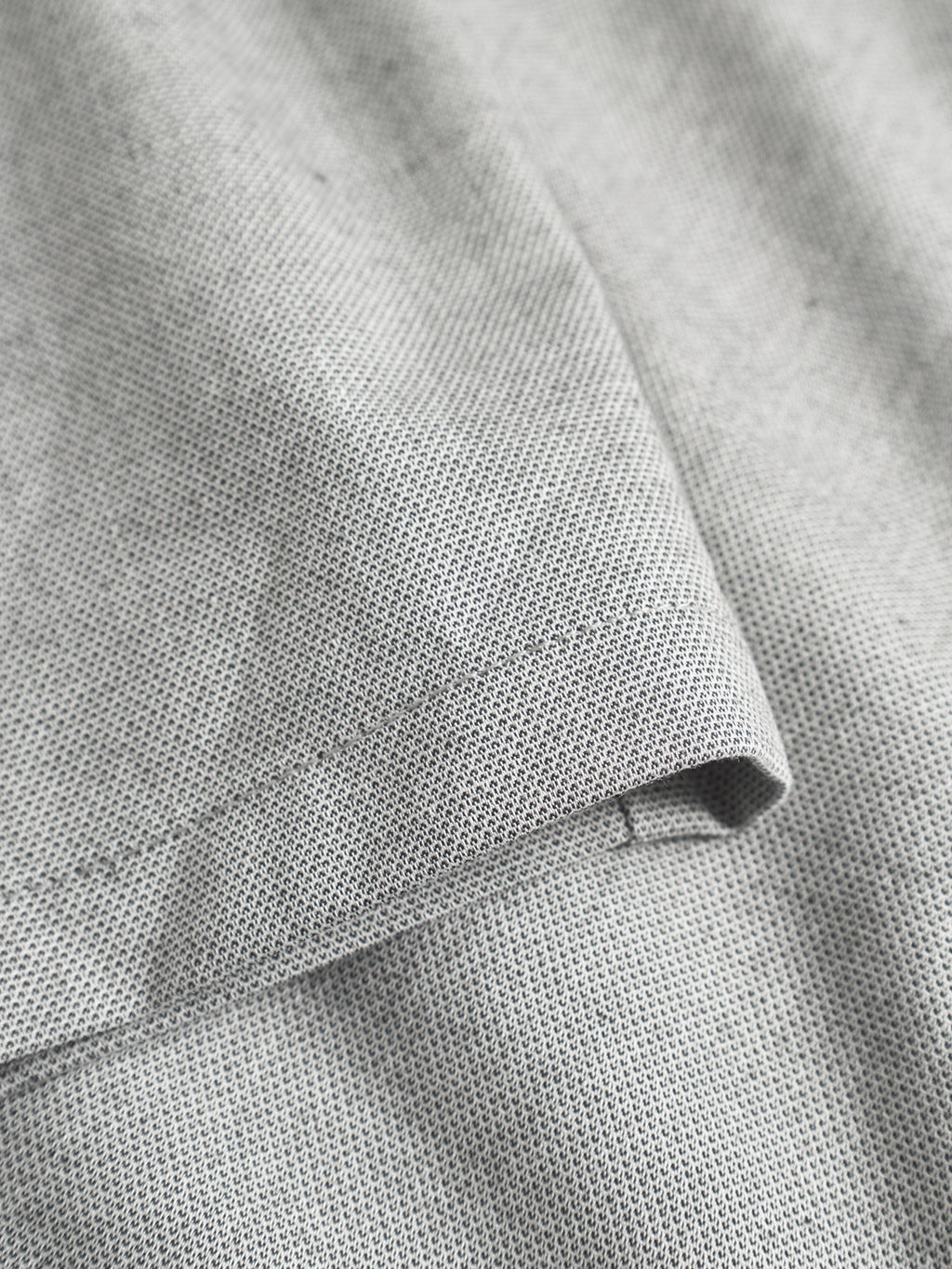 Close-up of the Monza Button Carre - Lt. Grey fabric by Gabba, featuring fine textured weave and a neatly folded edge—its soft, structured look is ideal for creating relaxed, versatile straight pants.