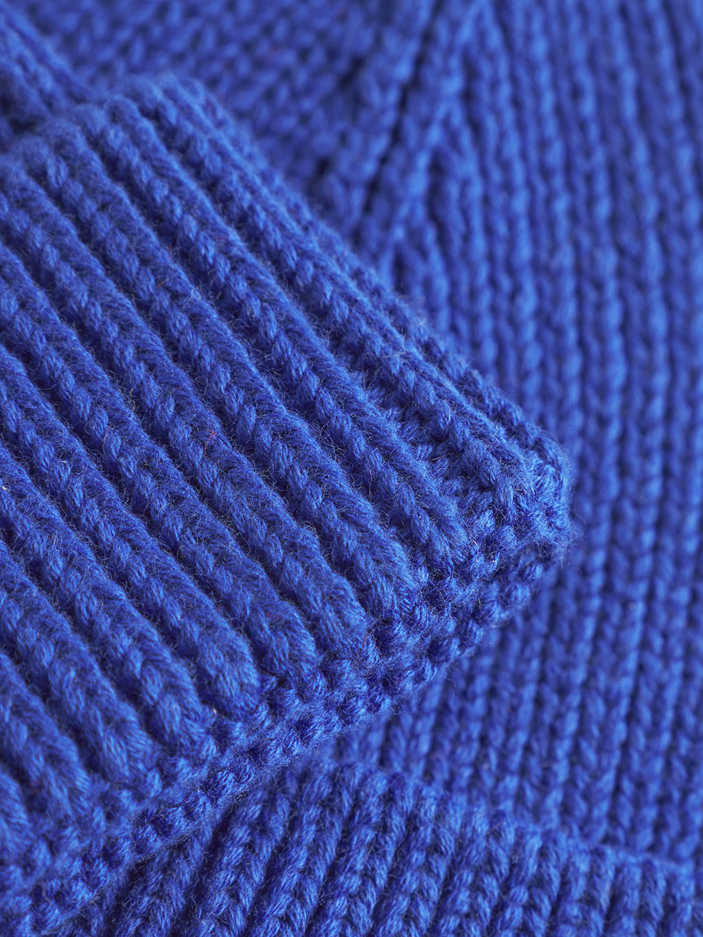 A close-up of vibrant blue fabric showcases overlapping layers, detailed stitching, and a plush texture, reminiscent of Gabbas New Mount Beanie - Blue.