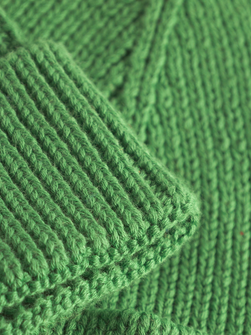 The New Mount Beanie - Green by Gabba features a close-up of its thick, soft, and uniformly ribbed knit. Its vibrant green color highlights the craftsmanship and detail.