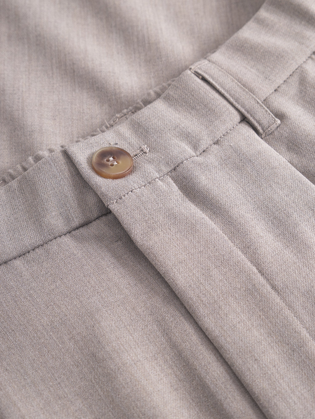 Close-up of the waistband on Gabba’s GABnapoli 19 Phin GRS - Sand trousers, highlighting the brown button, belt loop, visible stitching, pleats, and tailored finish on the beige fabric.