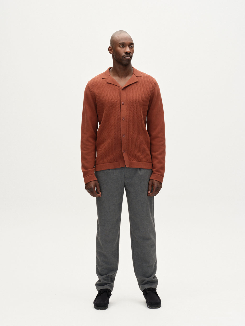 A man stands facing forward in a rust button-up shirt, Gabba Napoli 19 Phin GRS - Dk. Grey wool-viscose trousers, and black shoes against a plain white background.