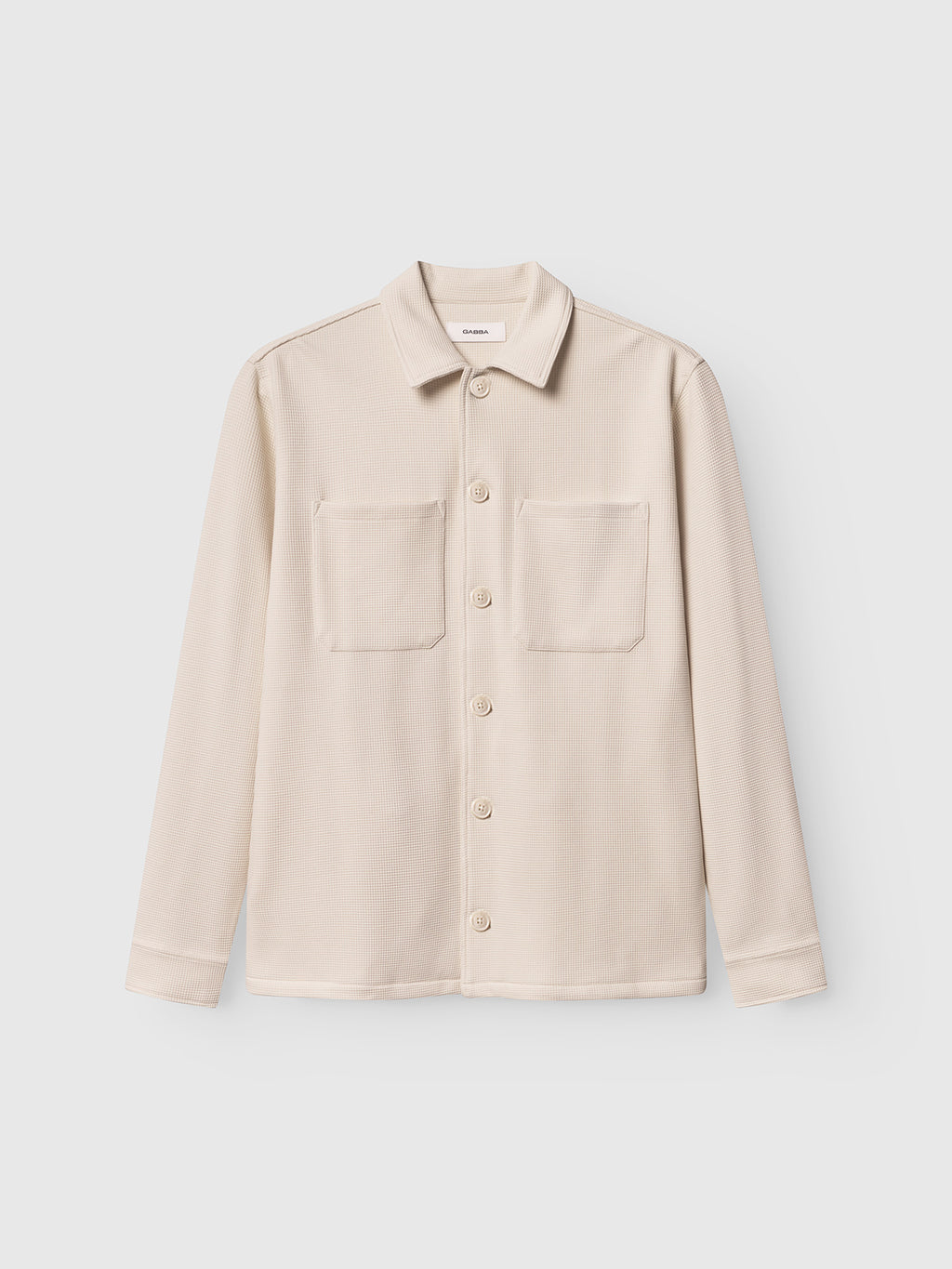 Beige shirt with two front pockets on a light gray background