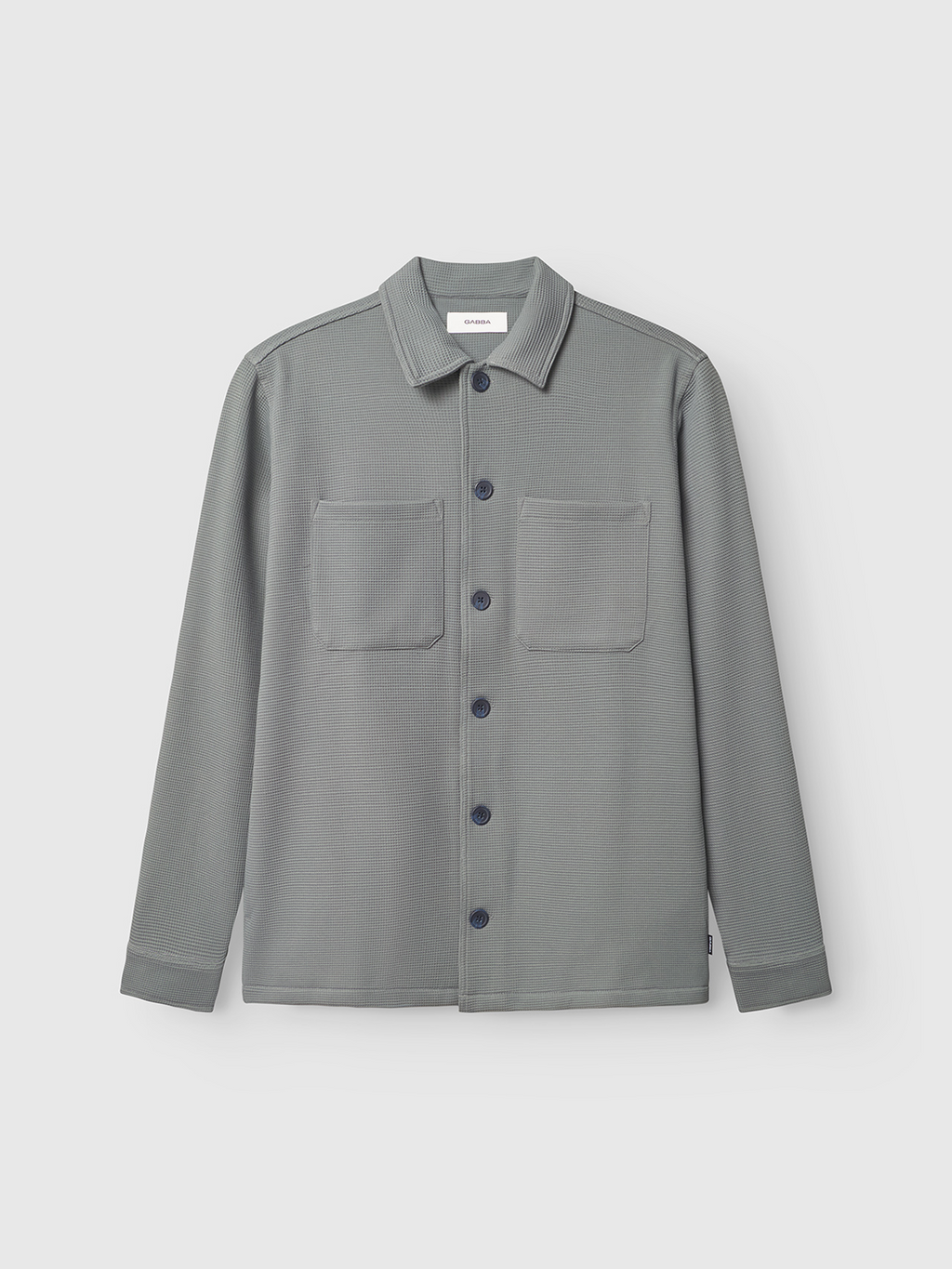 The Gabba Como Waff overshirt in Dust Sage Green features a waffle knit, button-down front, chest pockets, and a collar—ideal for layering. Displayed on a plain white background.