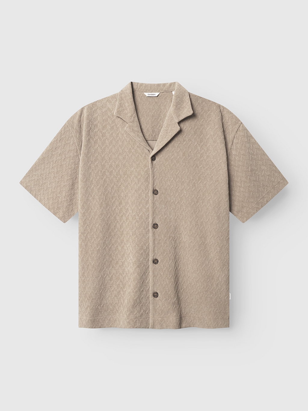 The Gabba Jens Over Diam SS overshirt in sand is a short-sleeve, light beige piece with a notched collar and subtle texture, shown against a plain white background.