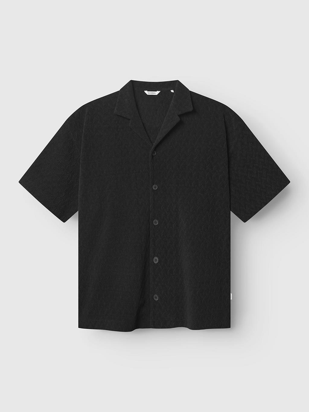 The Gabba Jens Over Diam SS - Black is a short-sleeved, oversized resort shirt with a subtle diamond jacquard velvet pattern, a resort collar, and relaxed fit, shown on a plain white background.