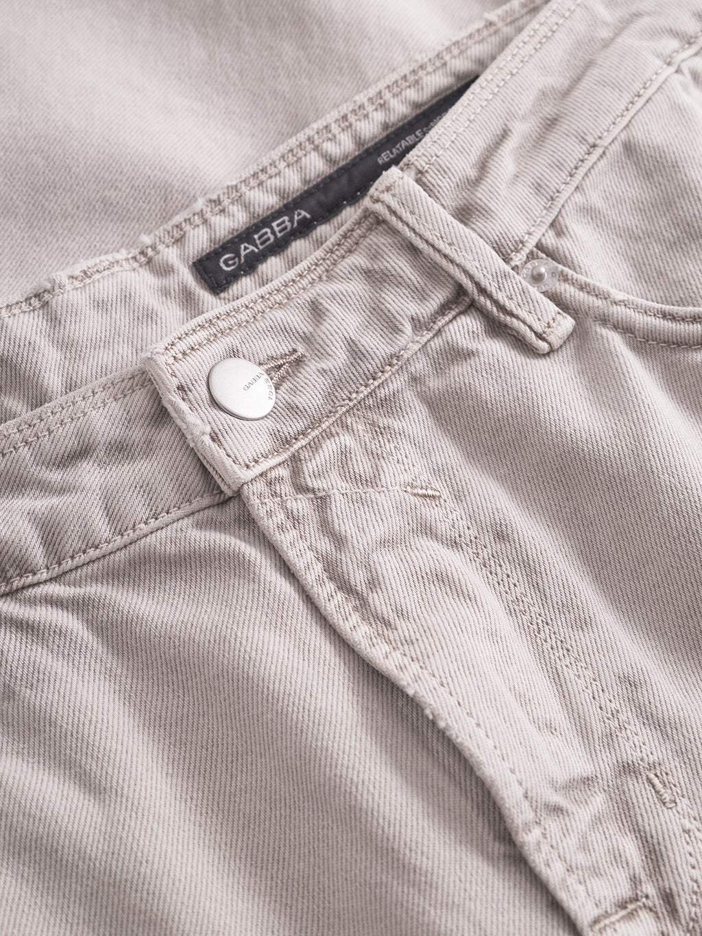Close-up of Gabba Max Glate - Sand denim jeans featuring a silver button, visible stitching, and a waistband label. Made from non-stretch cotton, the texture and fabric details are clearly highlighted.