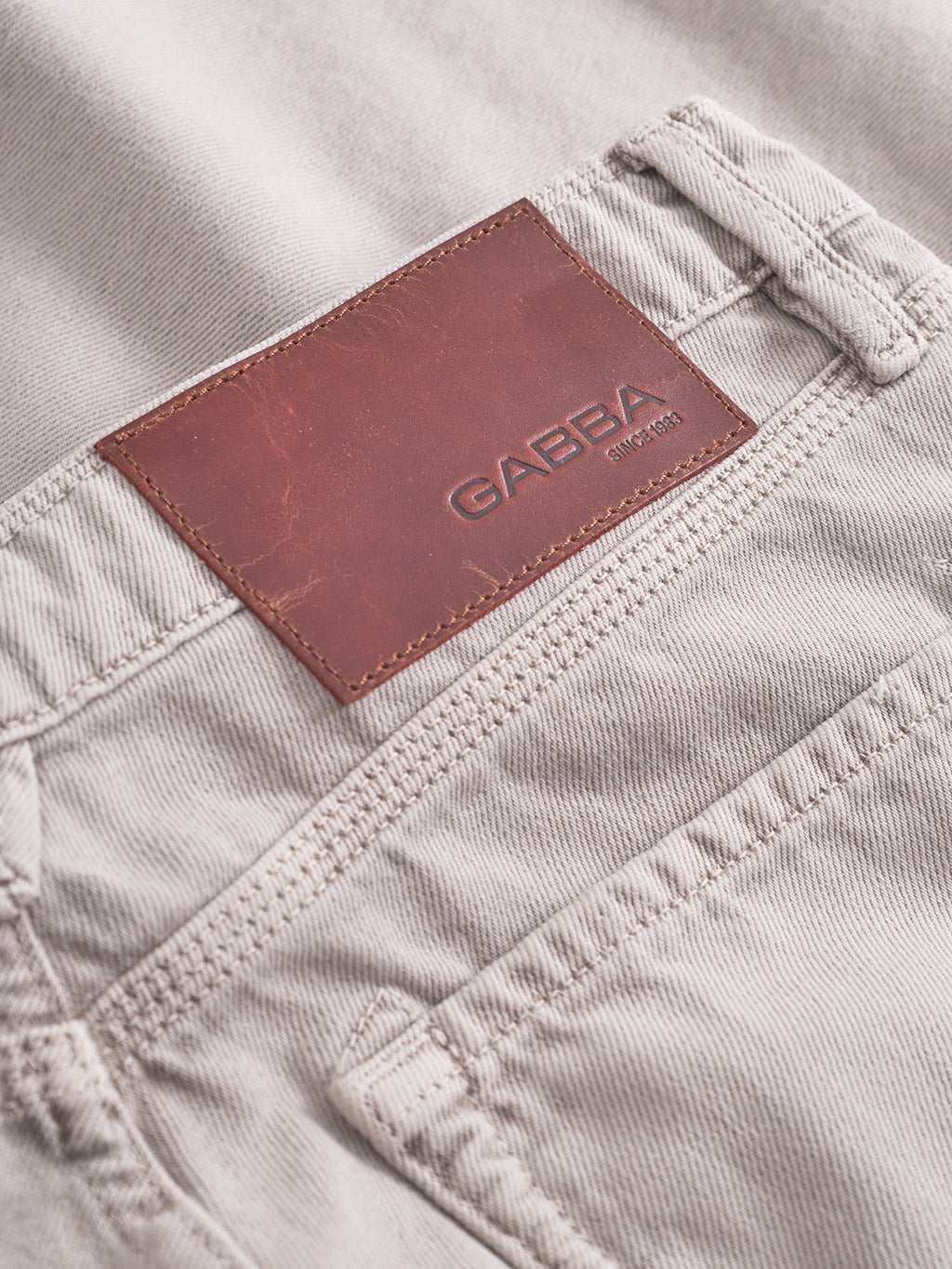 Close-up of the waistband and back pocket of Max Glate - Sand loose straight jeans by Gabba, in light beige denim with a brown leather patch embossed “Gabba Established 1983.” Made from non-stretch cotton for lasting comfort.