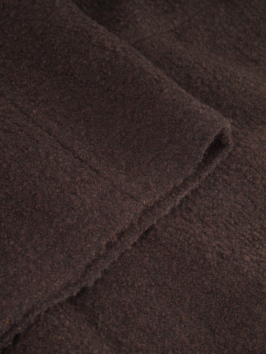 A close-up of Gabba's Milano Boucle - Brown shows its dark, textured wool with a soft, fuzzy finish and overlapping edges—perfect for creating a stylish boucle coat or other textured designs.