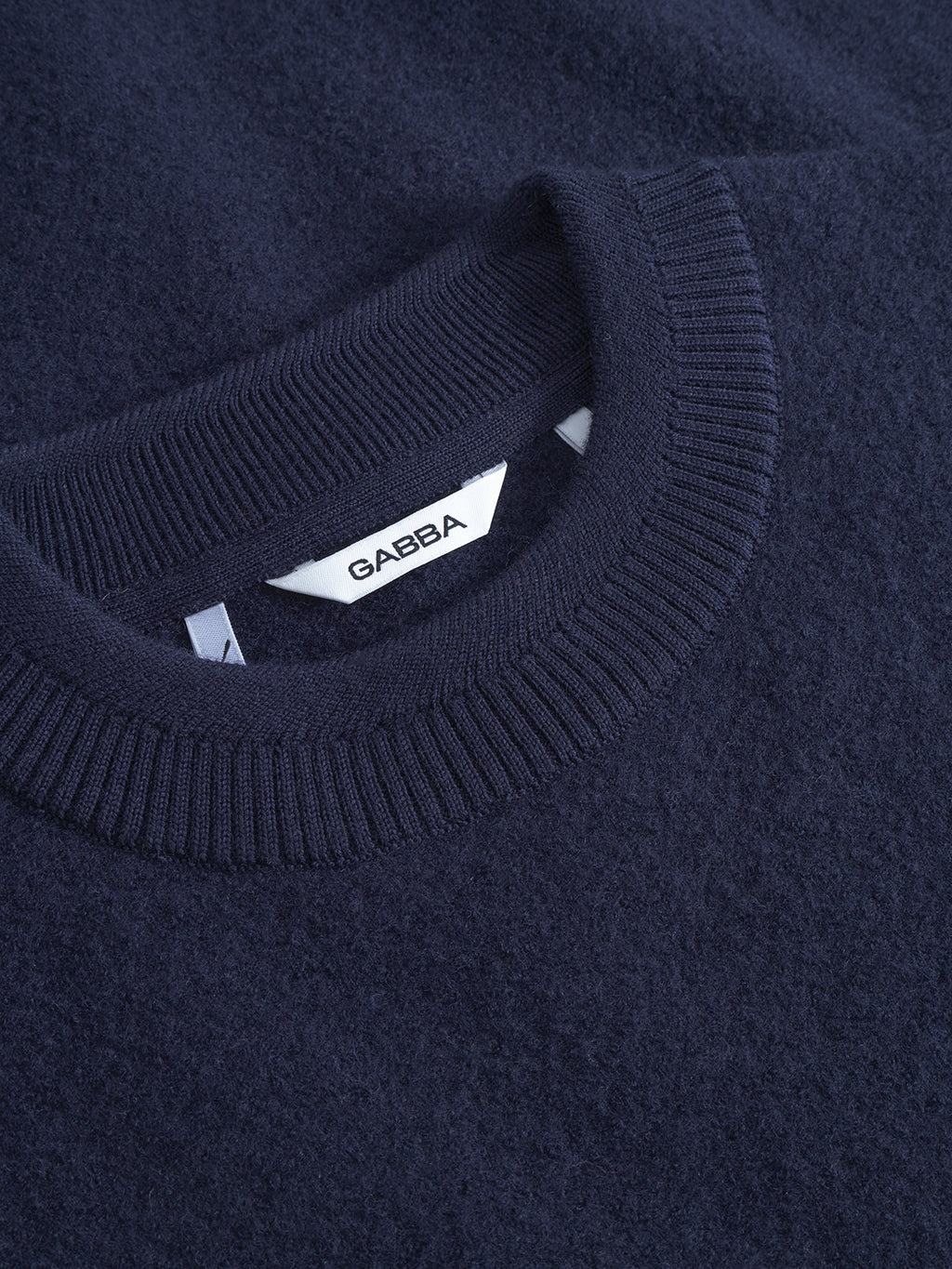 Close-up of the Bristol Led - Navy sweater by Gabba, featuring a ribbed crew neckline and a white label reading GABBA inside the collar. The soft, slightly textured knit is ideal for cozy winter wear.