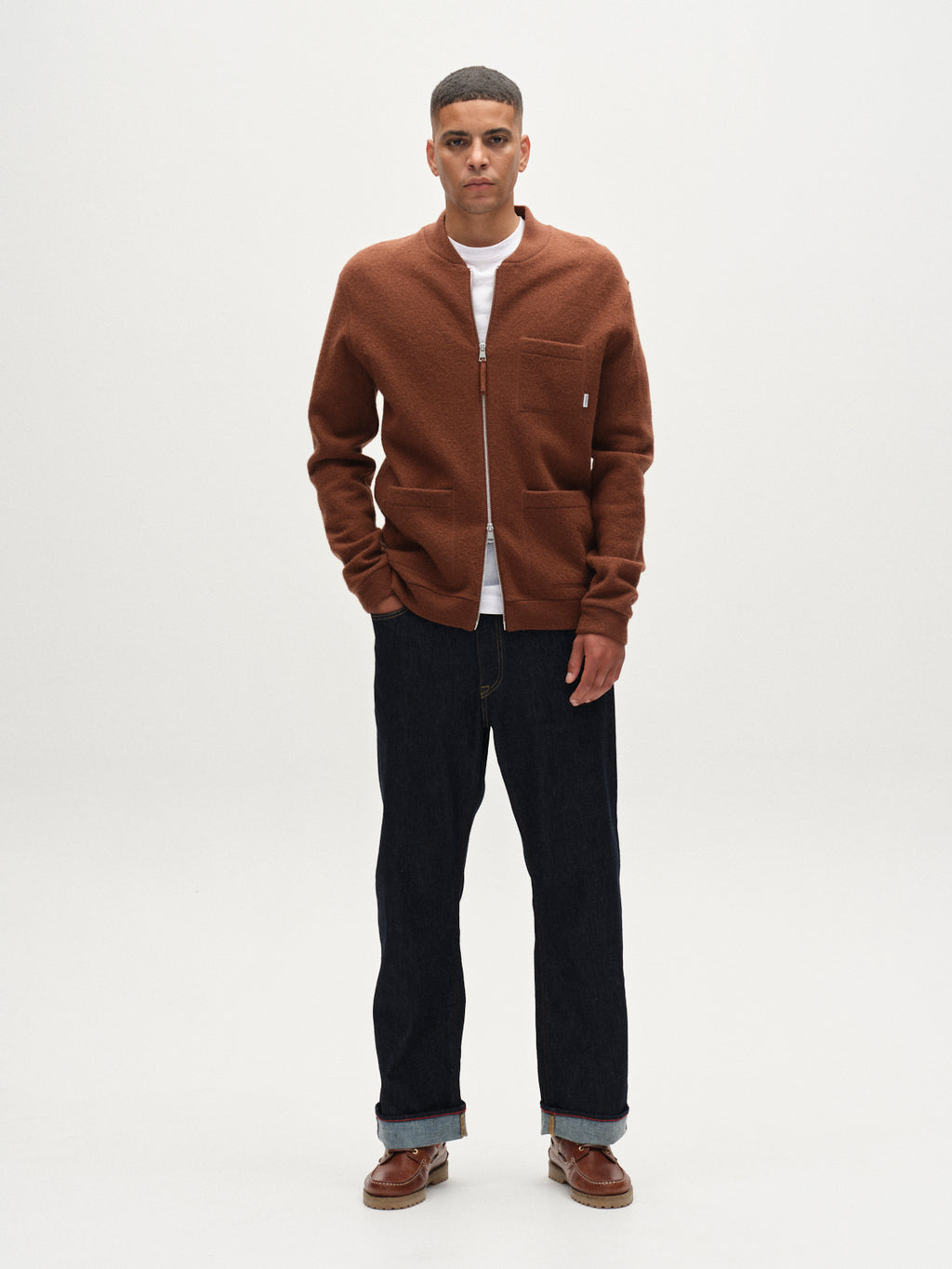 A man faces forward with hands in pockets, wearing the Gabba Cardiff Led wool bomber jacket in brownish, styled with a white t-shirt, dark jeans, and brown shoes against a plain white background.
