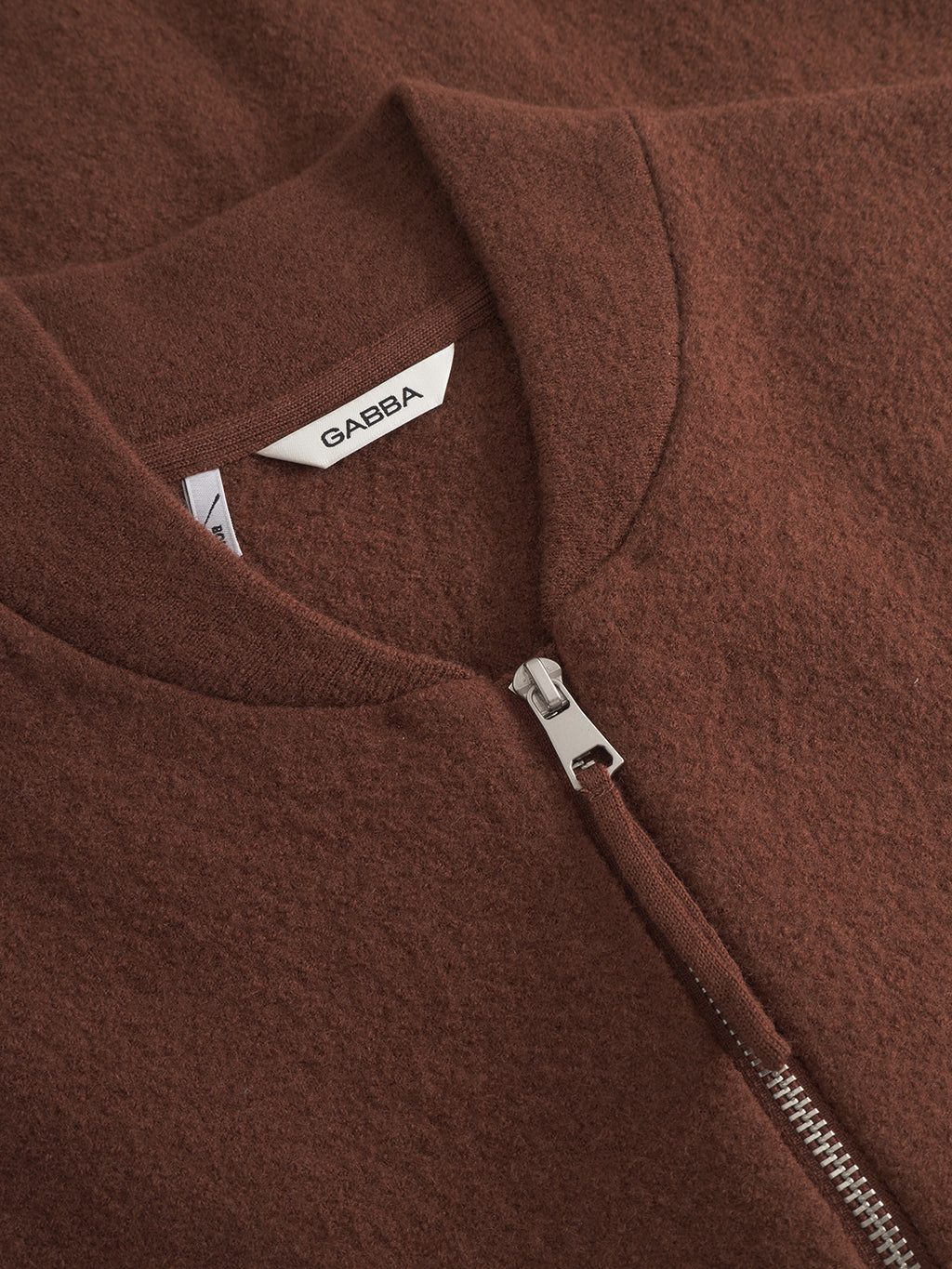 Close-up of the Gabba Norwich Led - Brownish wool zip-up jacket, perfect for layering, featuring a silver zipper and a white Gabba label inside the collar.