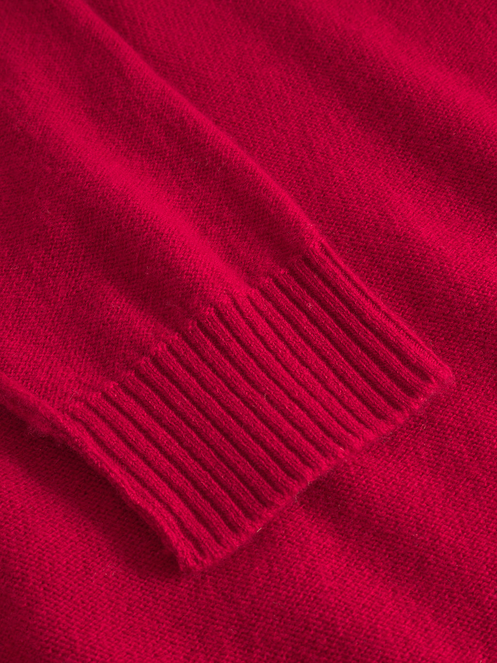 Close-up of the Gabba Tokota Aico LS - Red sweater sleeve, featuring a ribbed cuff that highlights the texture and fine stitching of this modern Merino wool knit.