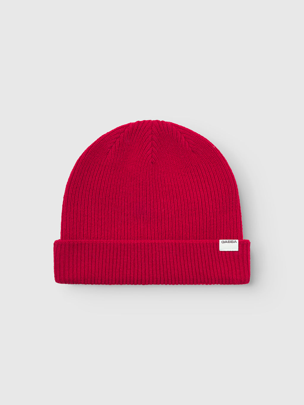 The Gabba Biella Aico - Red is a vibrant red ribbed knit beanie featuring a folded brim and a small white rectangular front label, shown on a light gray background.