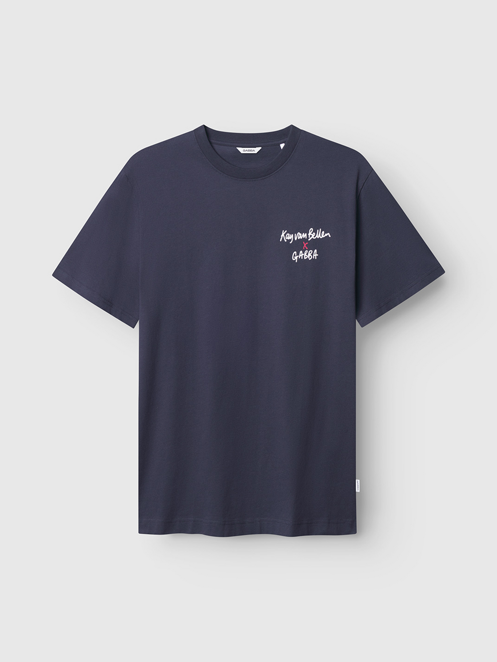 A plain navy blue organic cotton tee, the Gabba Dune Kay Man SS GOTS, features white Kay van Bellen GAEA text on the left chest. Displayed on a light gray background, its Japanese-inspired minimalism offers a timeless look.
