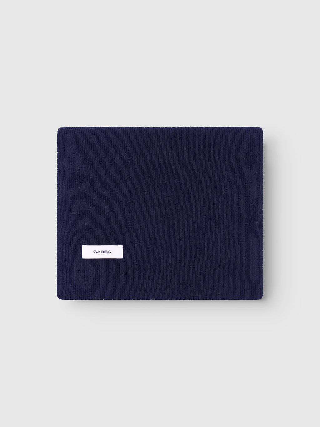 A neatly folded Biwa Aico - Navy ribbed knit scarf by Gabba, featuring a small white rectangle tag, is displayed on a light gray background.